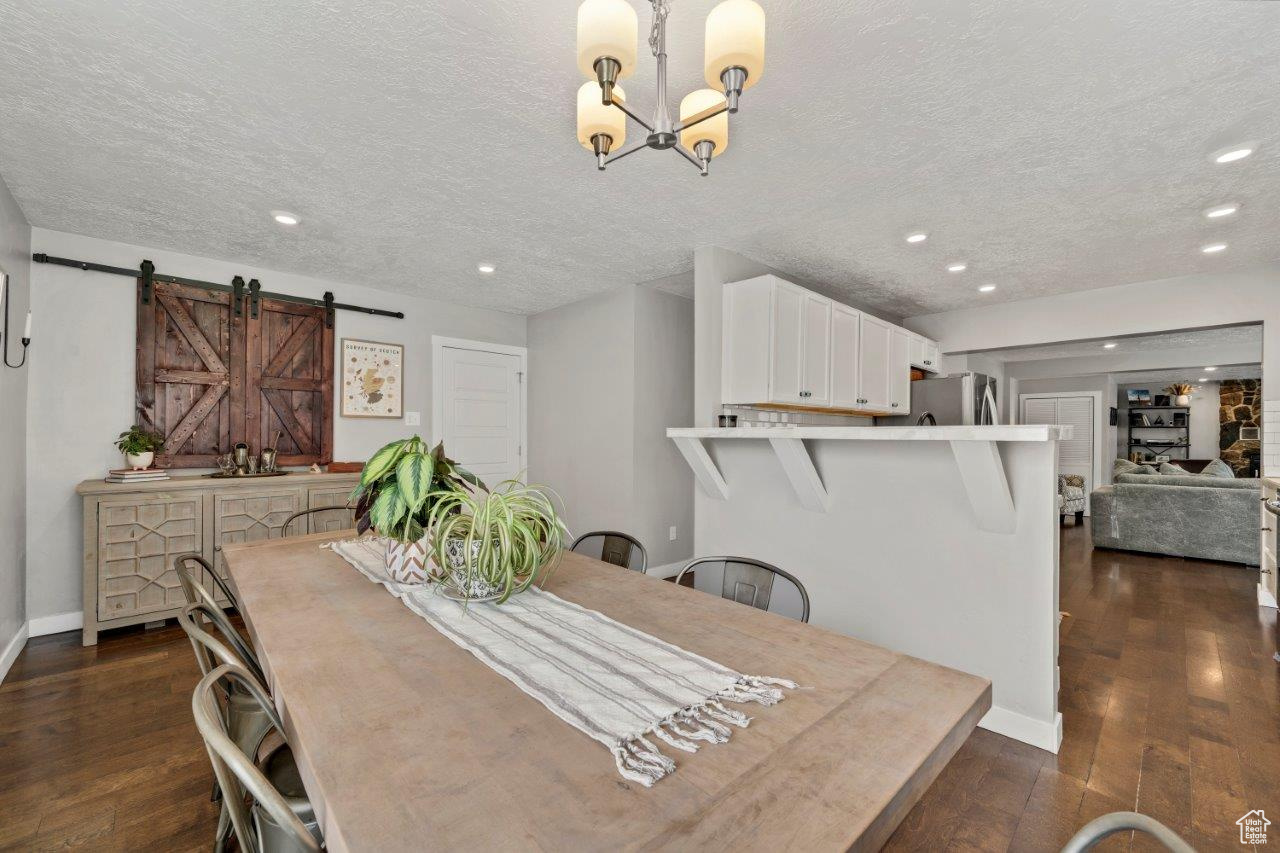 Dining area with dark hardwood / wood-style flooring, a barn door, and a textured ceiling