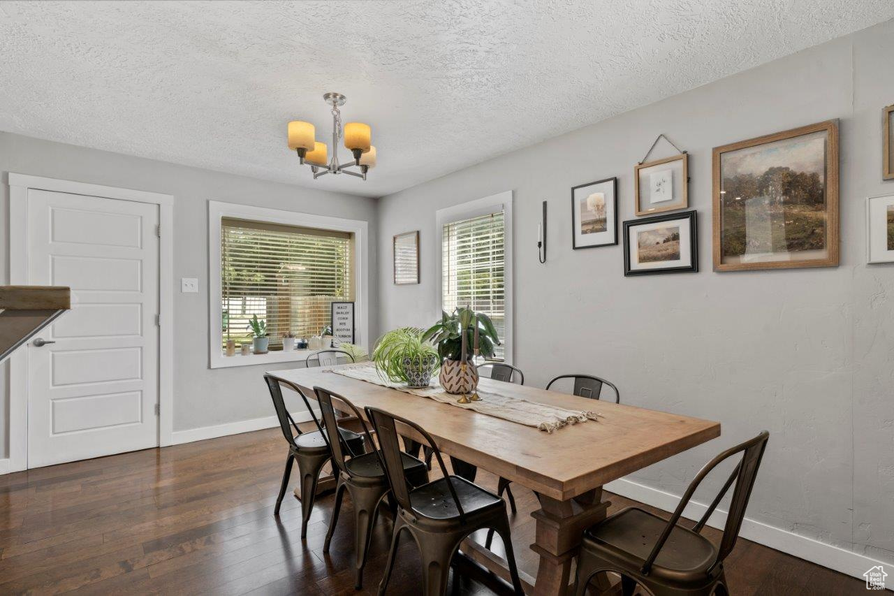 Dining room featuring a textured ceiling, dark hardwood / wood-style floors, and a chandelier