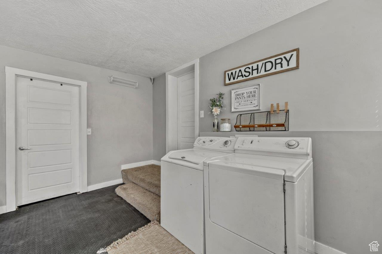 Laundry room with a textured ceiling, washer and clothes dryer, and carpet