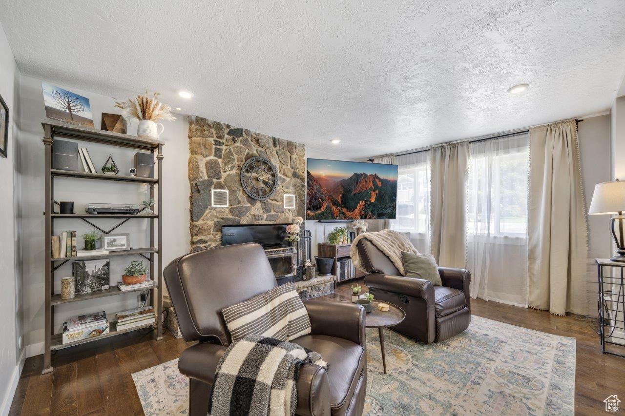 Living room with a fireplace, dark hardwood / wood-style floors, and a textured ceiling