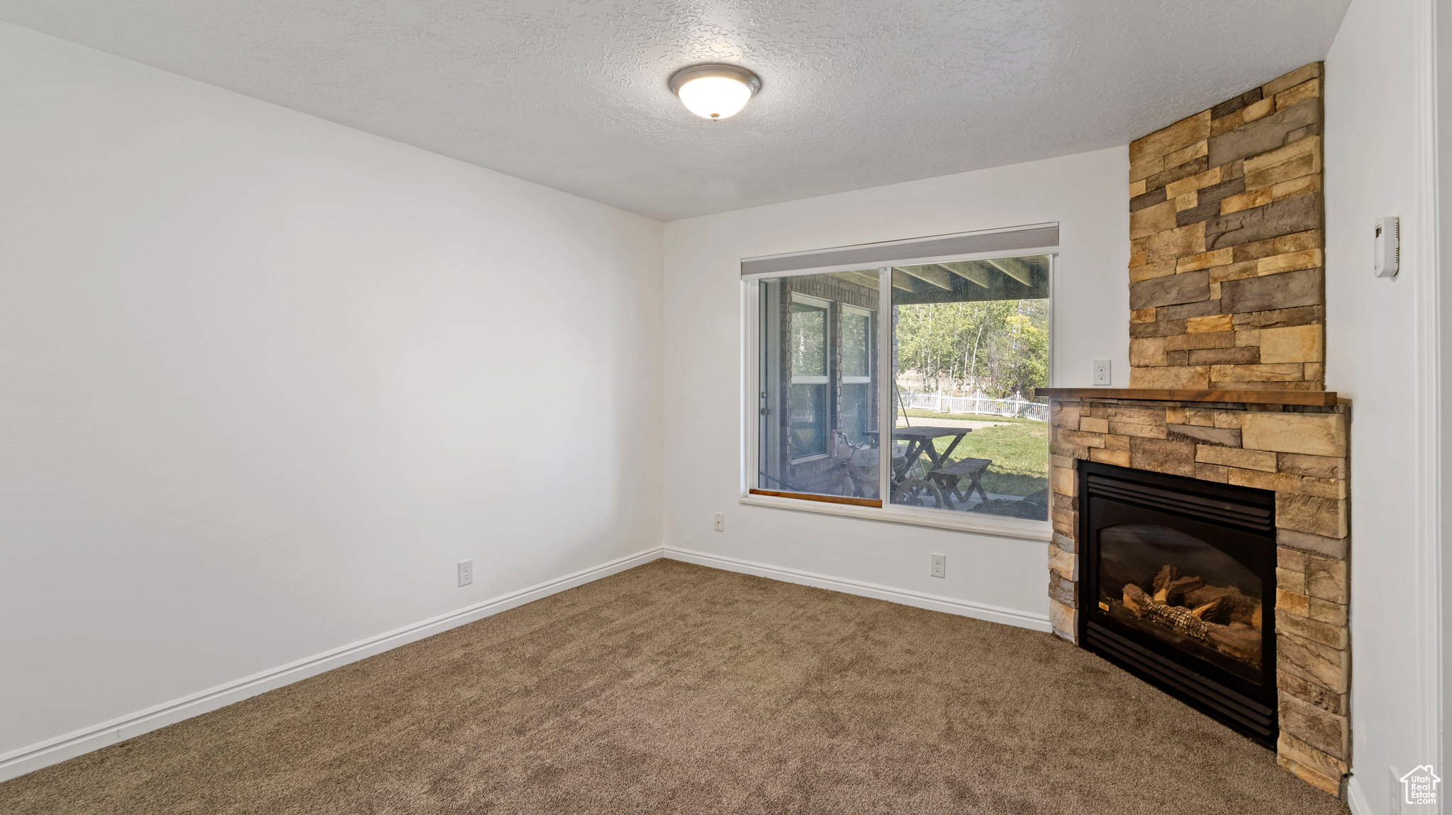 Unfurnished living room with a fireplace, a textured ceiling, and carpet floors