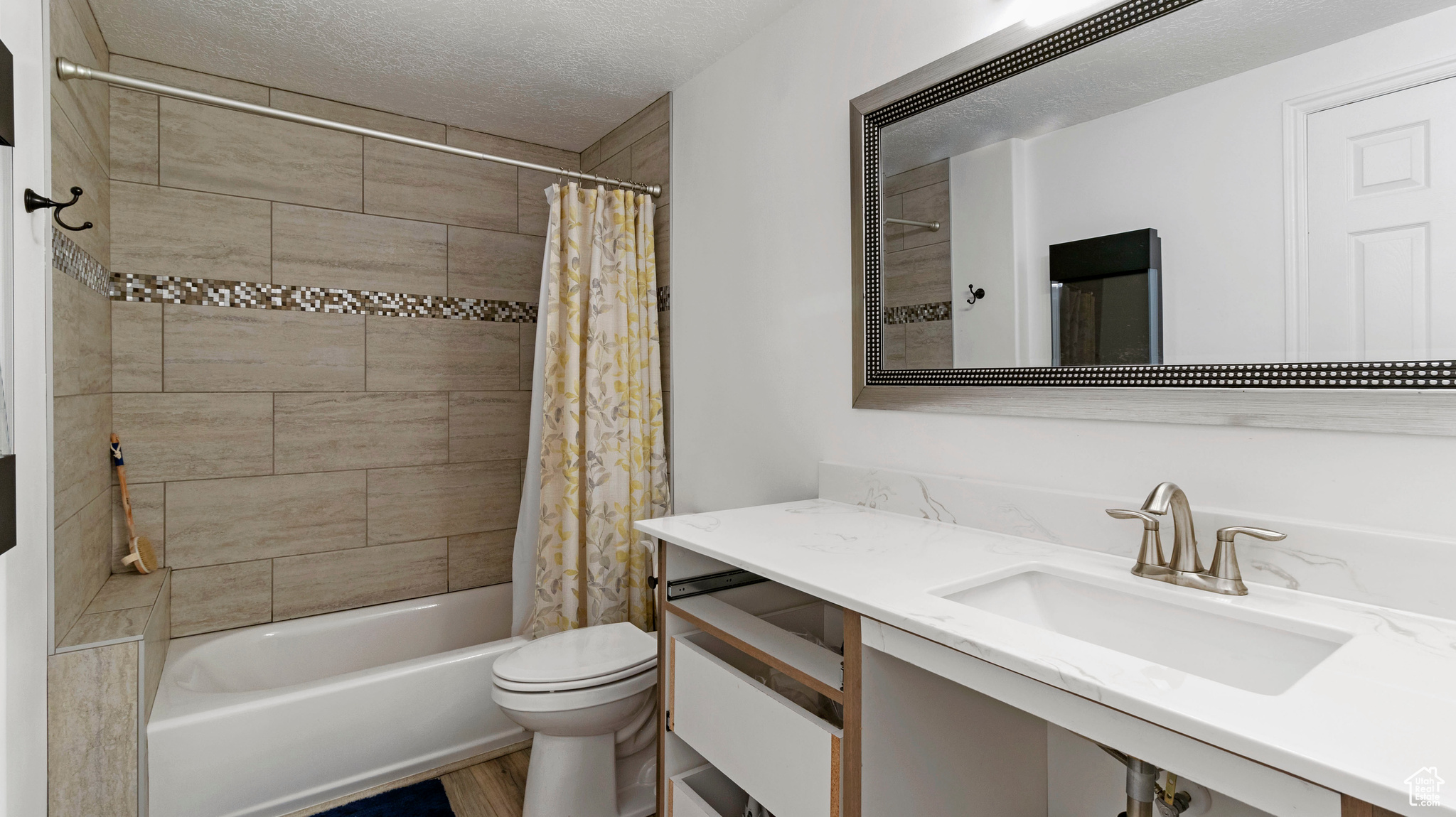 Full bathroom with vanity, toilet, shower / tub combo, and a textured ceiling