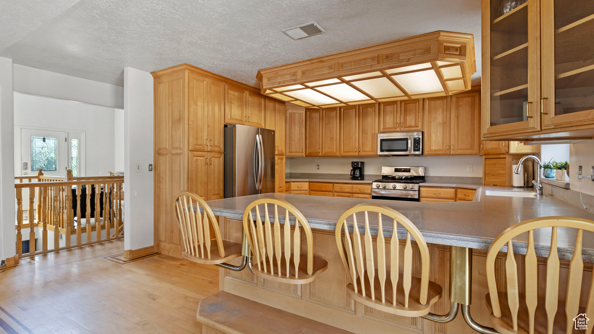 Kitchen featuring light hardwood / wood-style flooring, stainless steel appliances, sink, kitchen peninsula, and a breakfast bar area