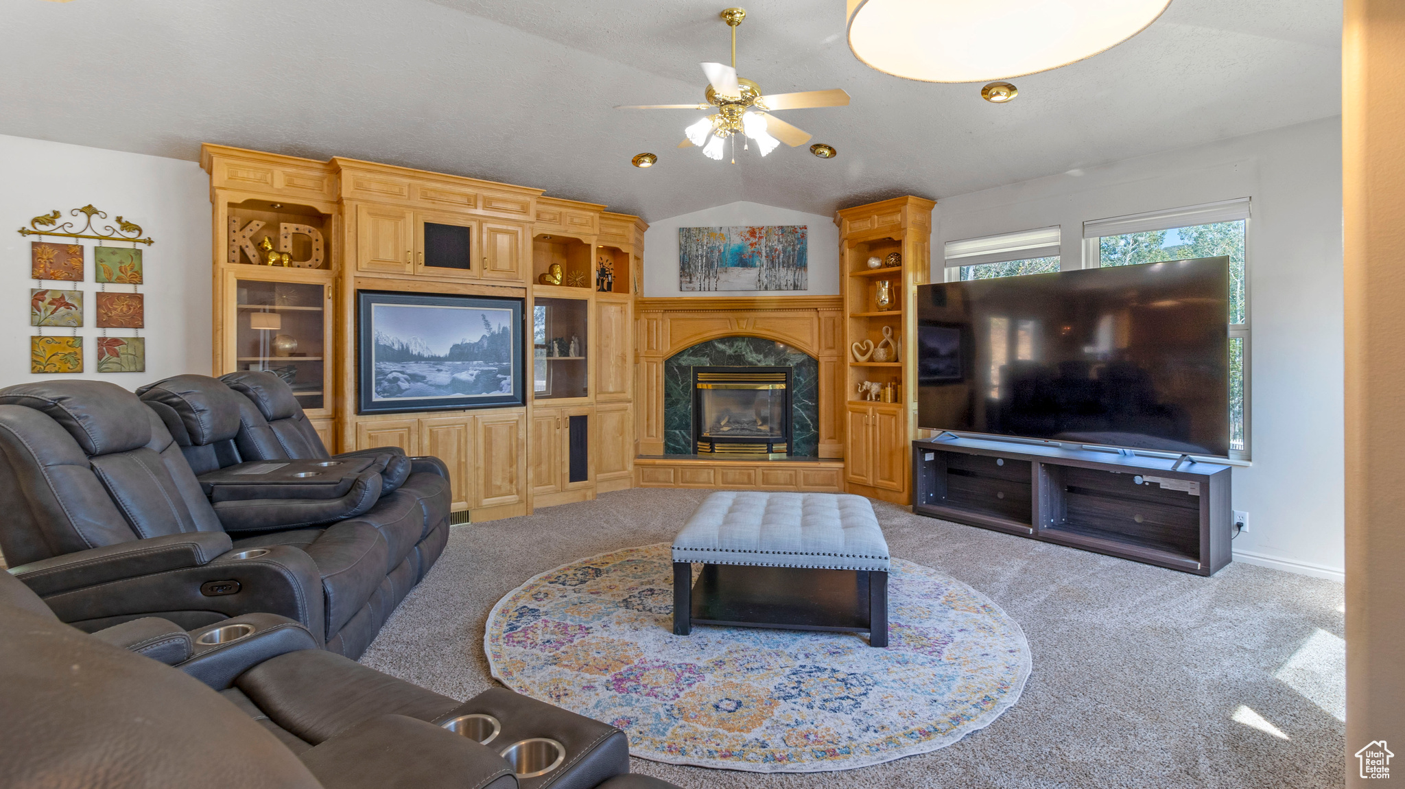 Living room with ceiling fan, carpet floors, a fireplace, and vaulted ceiling