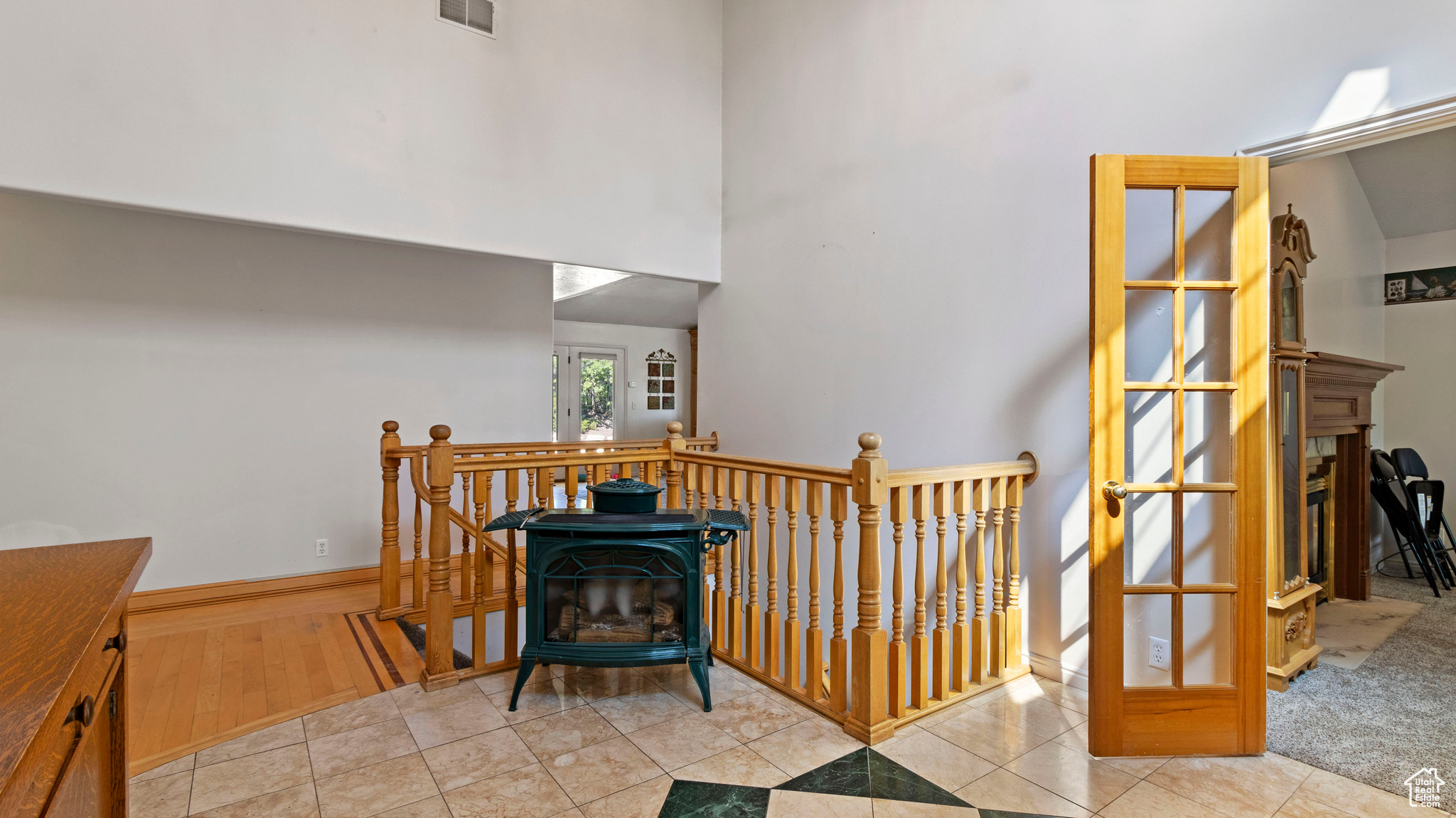 Interior space with a high ceiling, wood-type flooring, a fireplace, and a wood stove