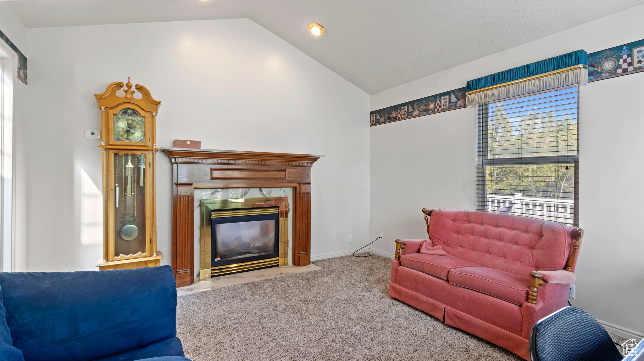 Carpeted living room with a high end fireplace and lofted ceiling