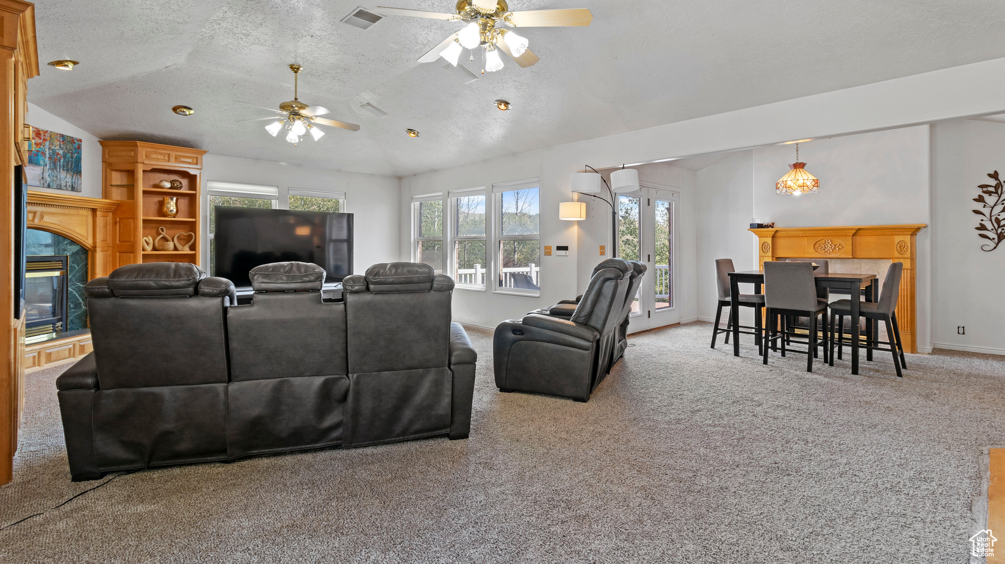 Living room featuring lofted ceiling, a textured ceiling, ceiling fan, and carpet