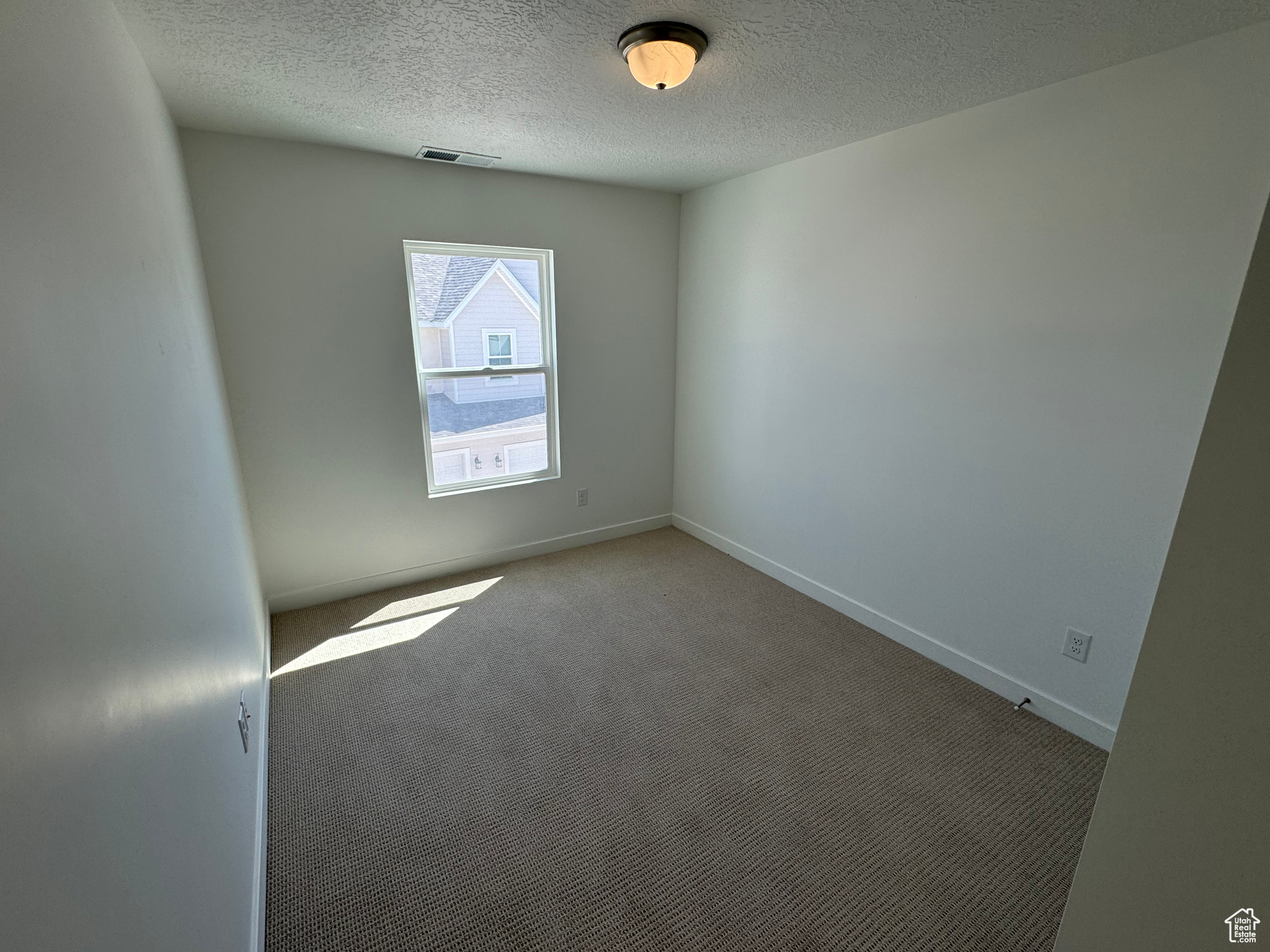 Empty room with carpet flooring and a textured ceiling