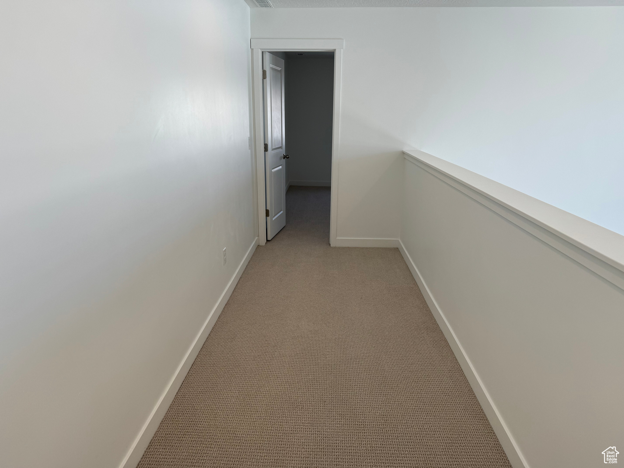 Hallway featuring light colored carpet