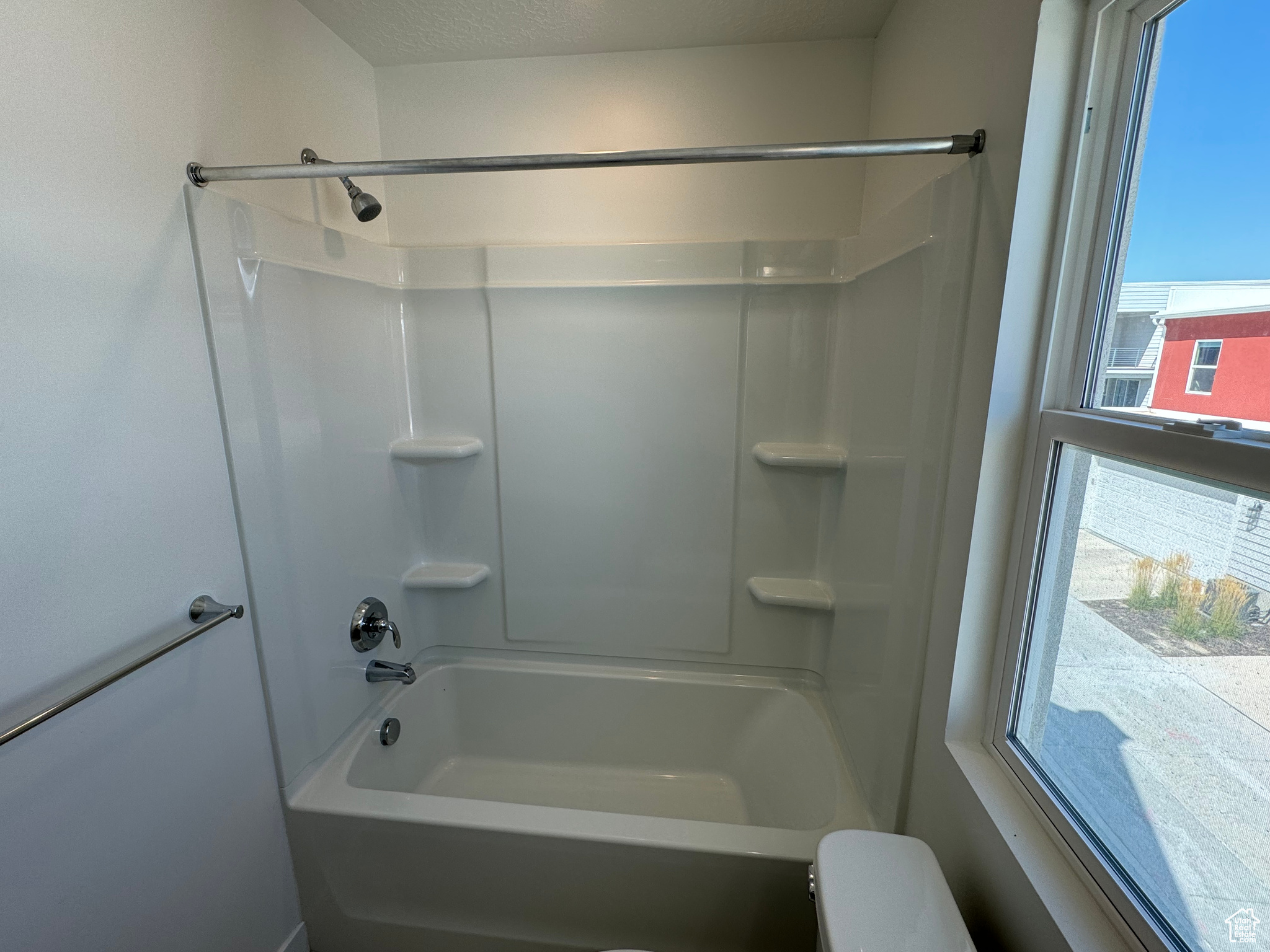 Bathroom with a textured ceiling, toilet, and bathing tub / shower combination