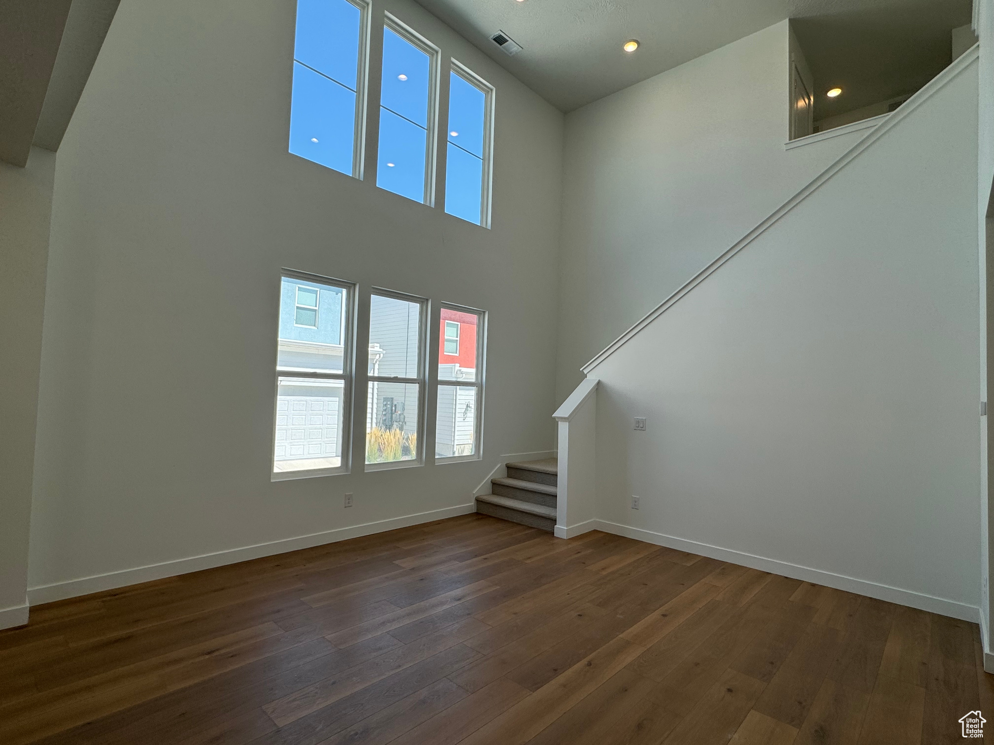 Unfurnished living room with a high ceiling and dark hardwood / wood-style floors