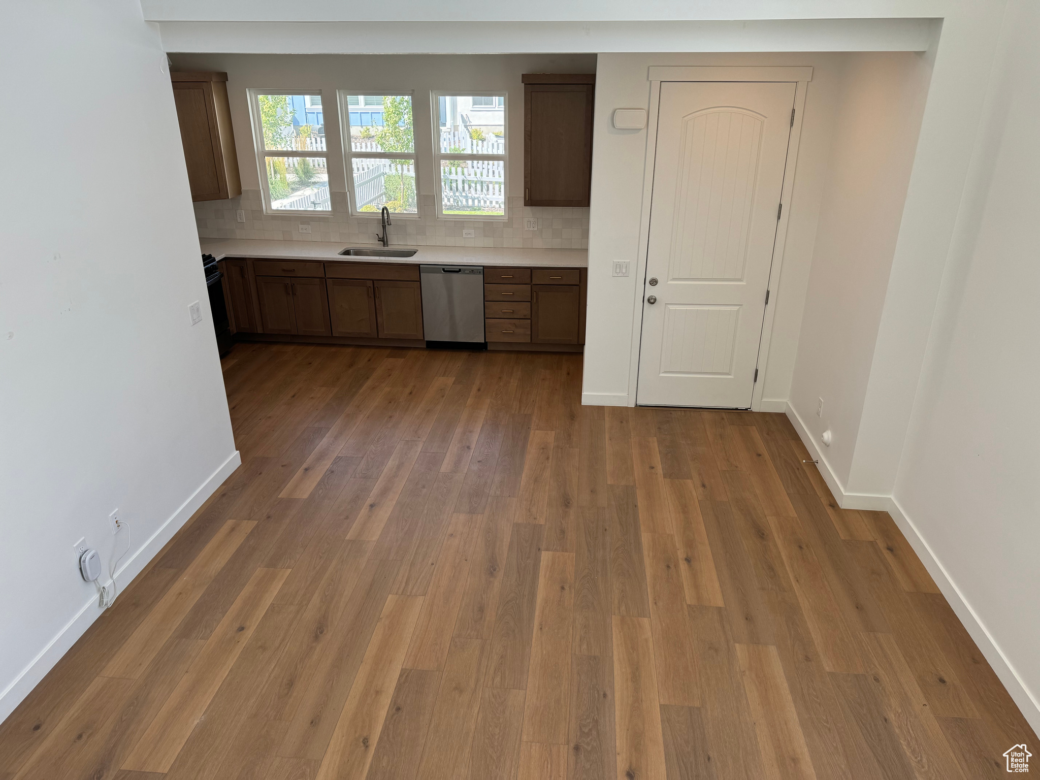 Kitchen featuring sink, light hardwood / wood-style floors, tasteful backsplash, and stainless steel dishwasher