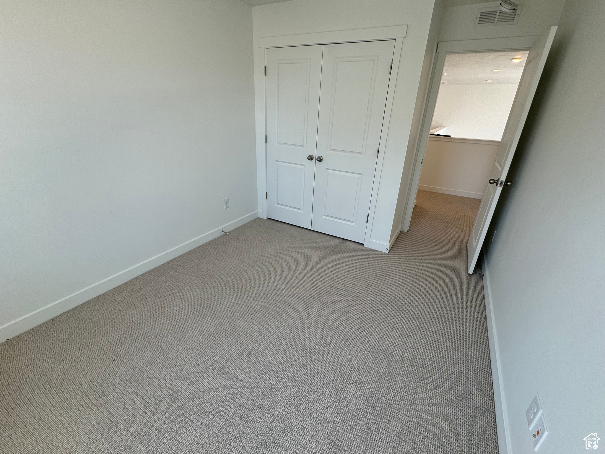 Unfurnished bedroom with a closet and light carpet