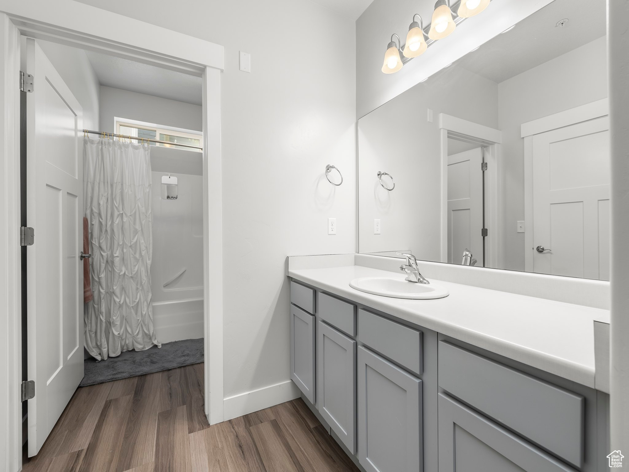 Bathroom with vanity, hardwood / wood-style flooring, and shower / bathtub combination with curtain