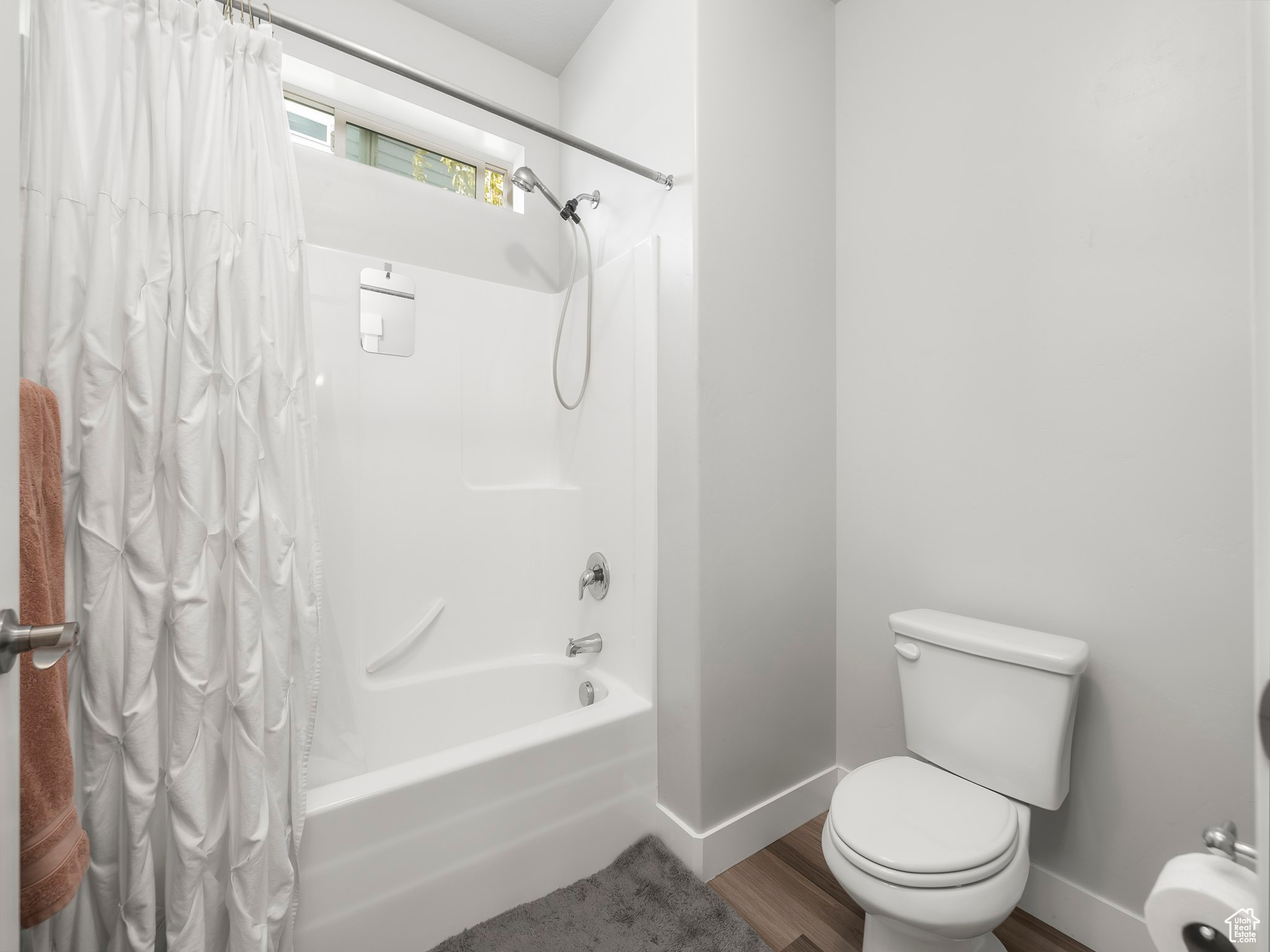 Bathroom featuring toilet, wood-type flooring, and shower / bathtub combination with curtain