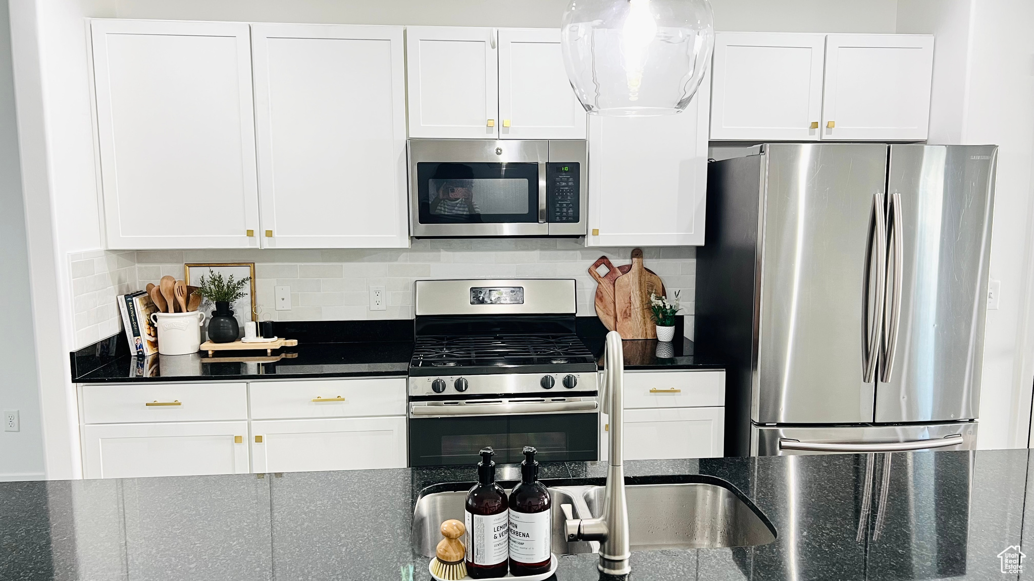 Kitchen featuring white cabinets, decorative Bedrosians Cloe tile backsplash, and appliances with stainless steel finishes