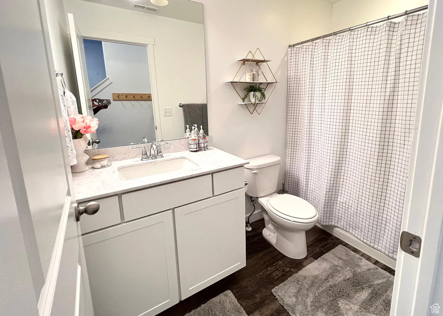 Bathroom with a shower, vanity, toilet, and dark vinyl flooring