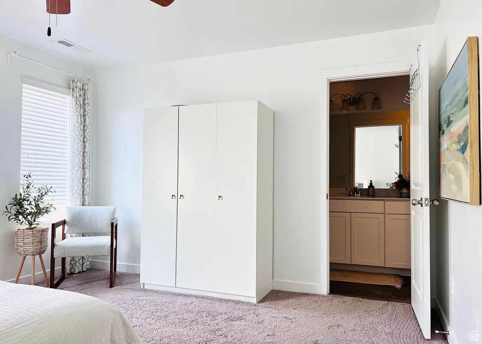 Bedroom featuring ceiling fan, connected bathroom, and light carpet