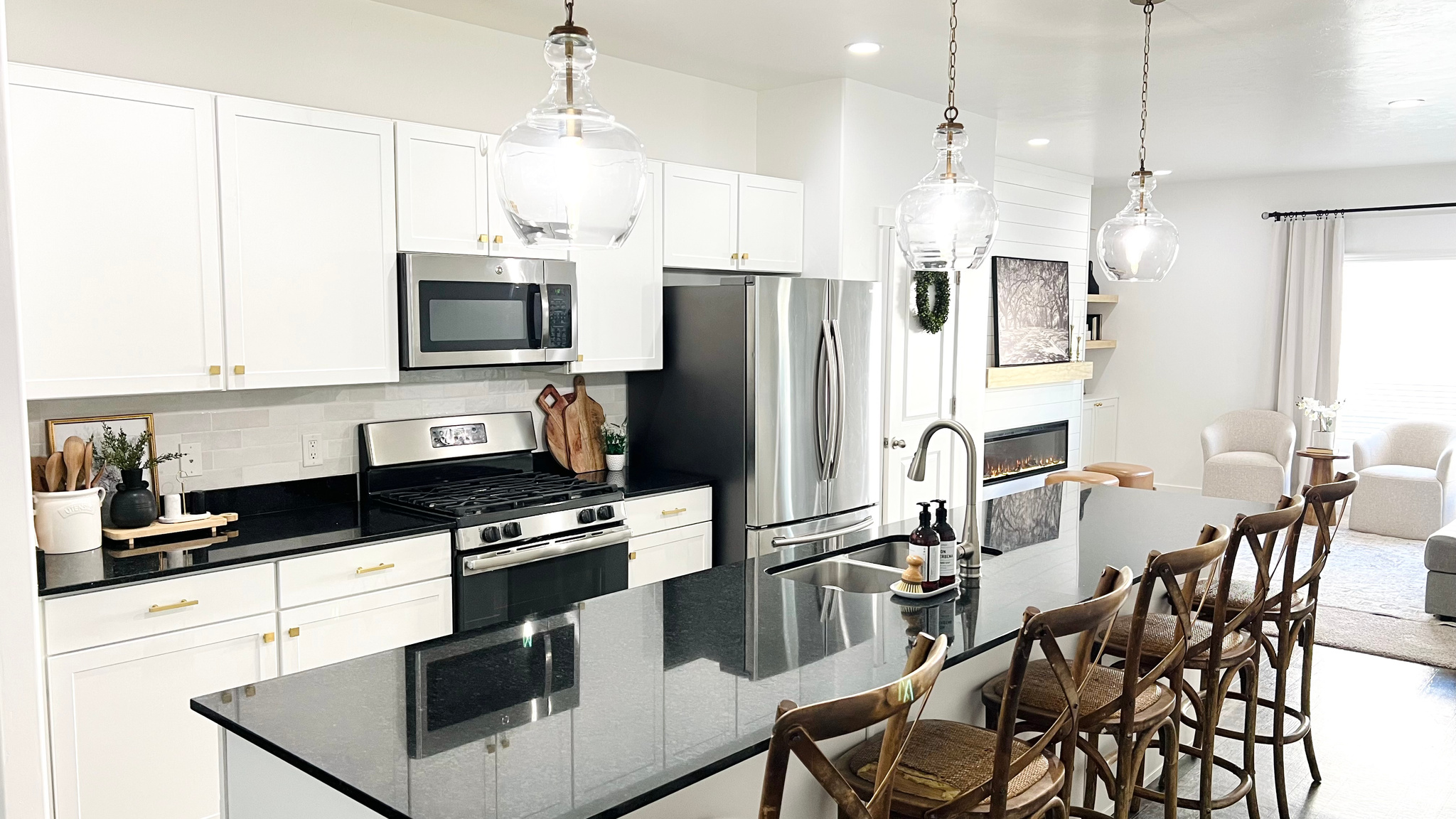 Kitchen featuring a kitchen island with sink, sink, appliances with stainless steel finishes, tasteful Bedrosians Cloe tile backsplash, and white cabinetry