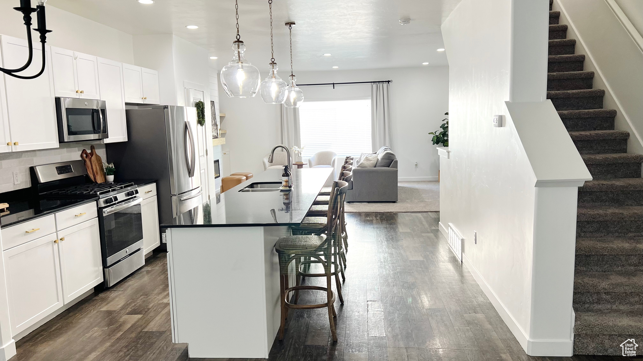 Kitchen featuring appliances with stainless steel finishes, a breakfast bar, sink, a center island with sink, and hanging light fixtures