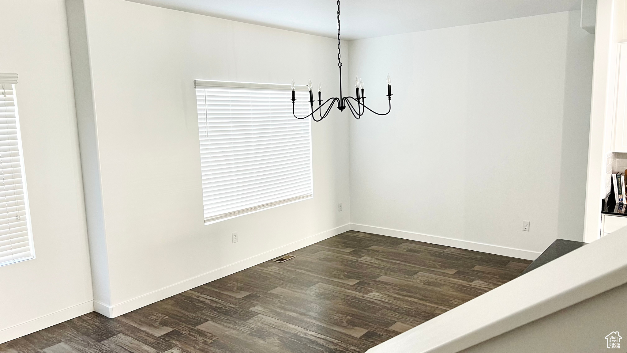 Unfurnished dining area with dark hardwood / wood-style floors and a notable chandelier