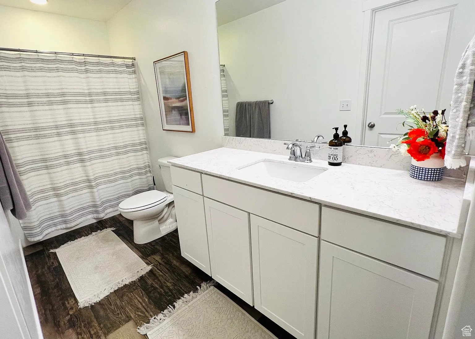 Bathroom with vanity, toilet, a shower, and dark vinyl floors