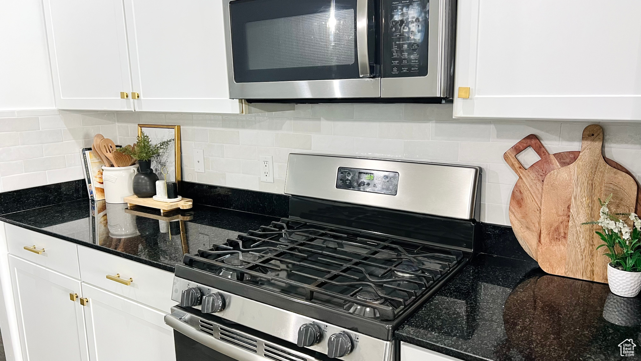 Kitchen featuring white cabinets, decorative Bedrosians Cloe tile backsplash, stainless steel appliances, and dark stone counters