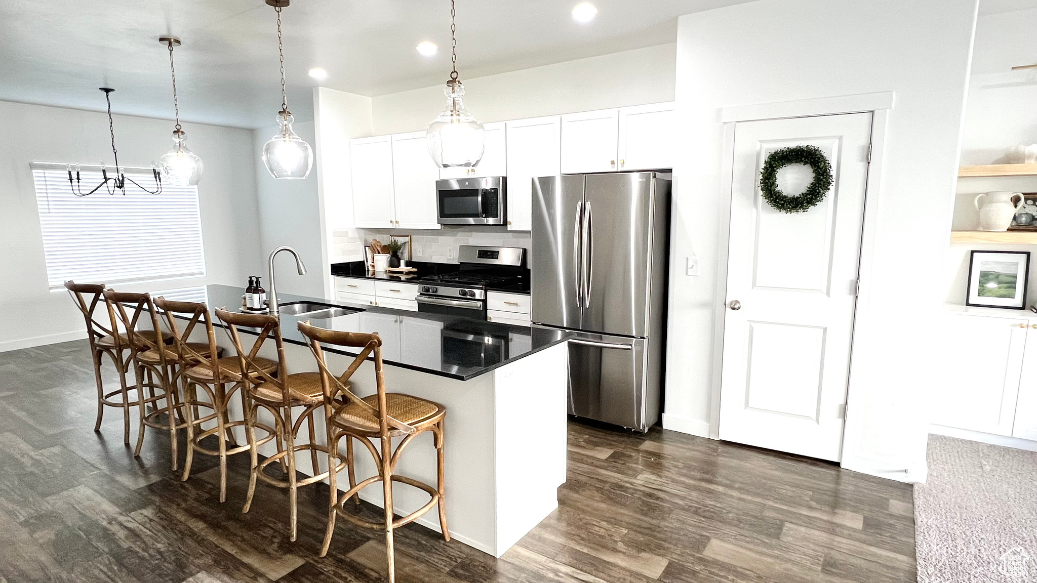 Kitchen featuring sink, a breakfast bar area, an island with sink, white cabinetry, and stainless steel appliances