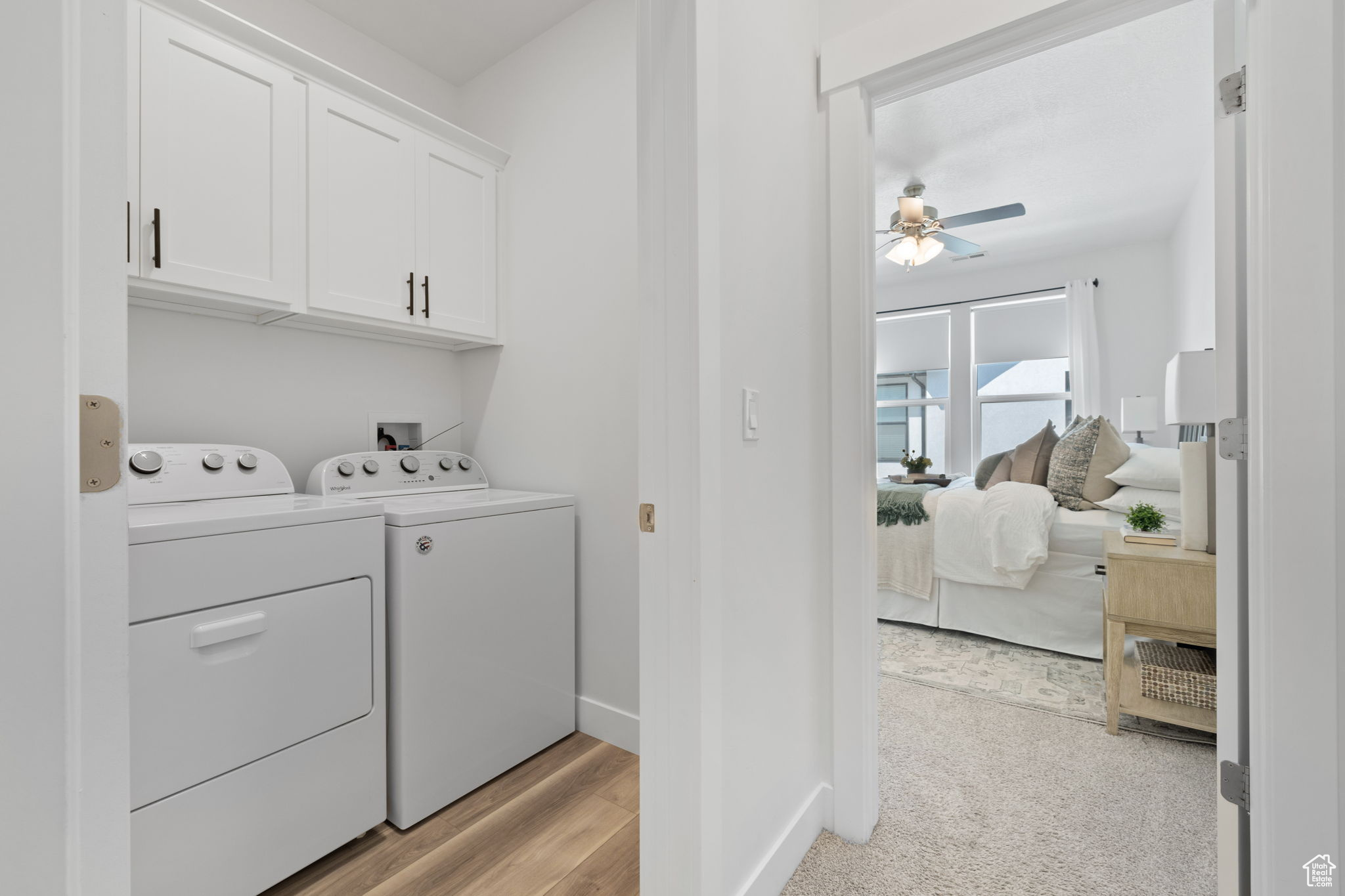 Laundry room with light hardwood / wood-style flooring, cabinets, washing machine and dryer, and ceiling fan