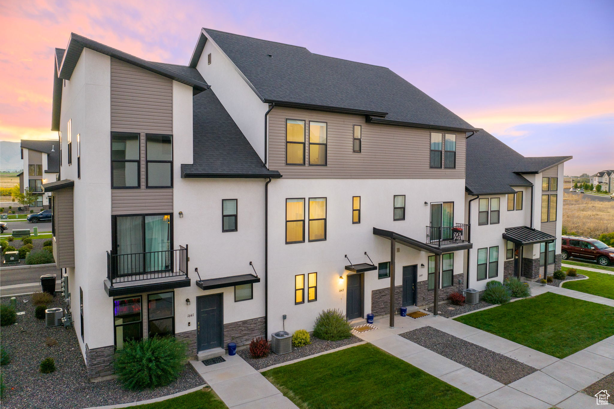 View of front of house featuring a yard, central AC, and a balcony