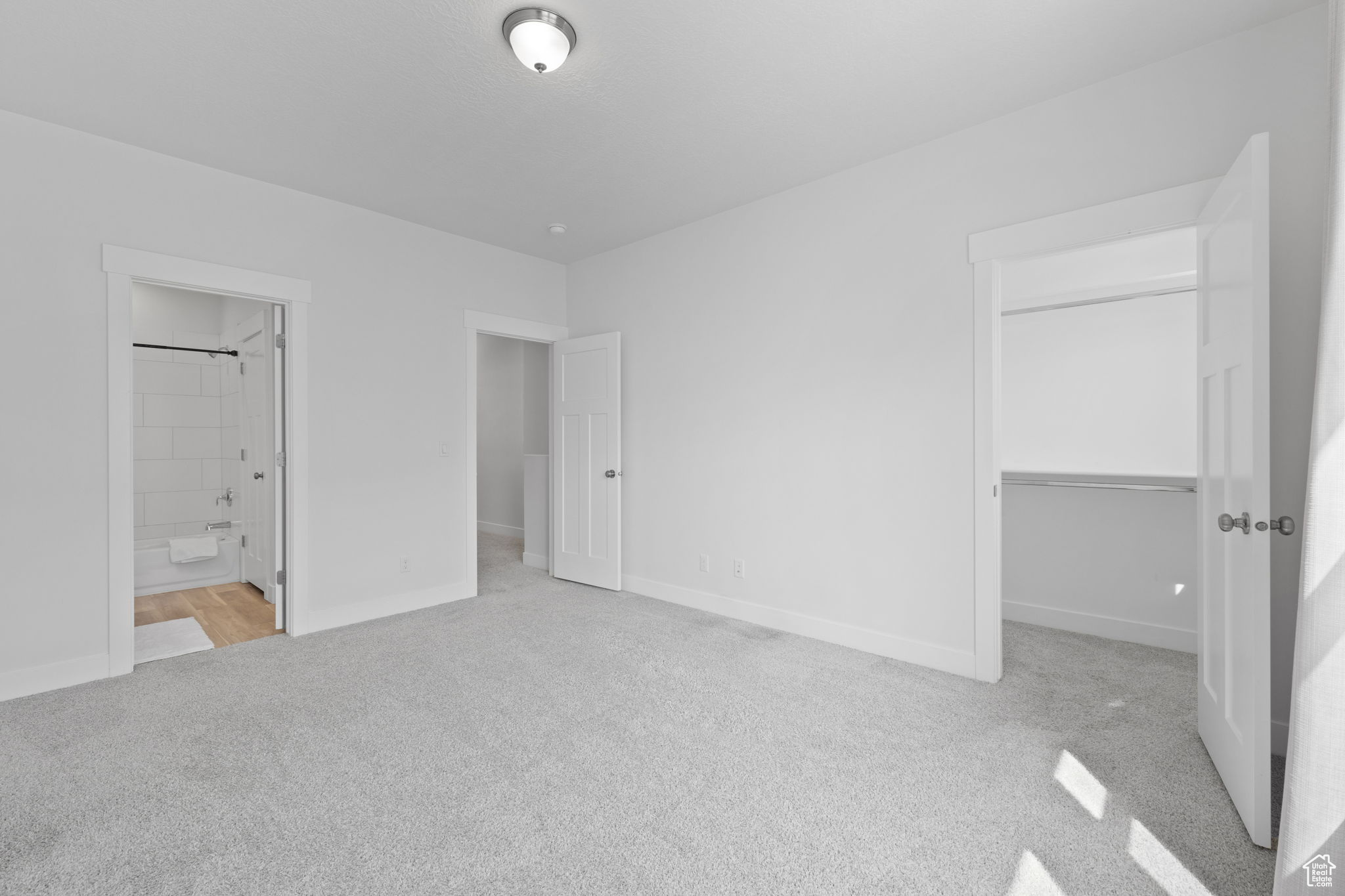 Unfurnished bedroom featuring light colored carpet, connected bathroom, and a closet