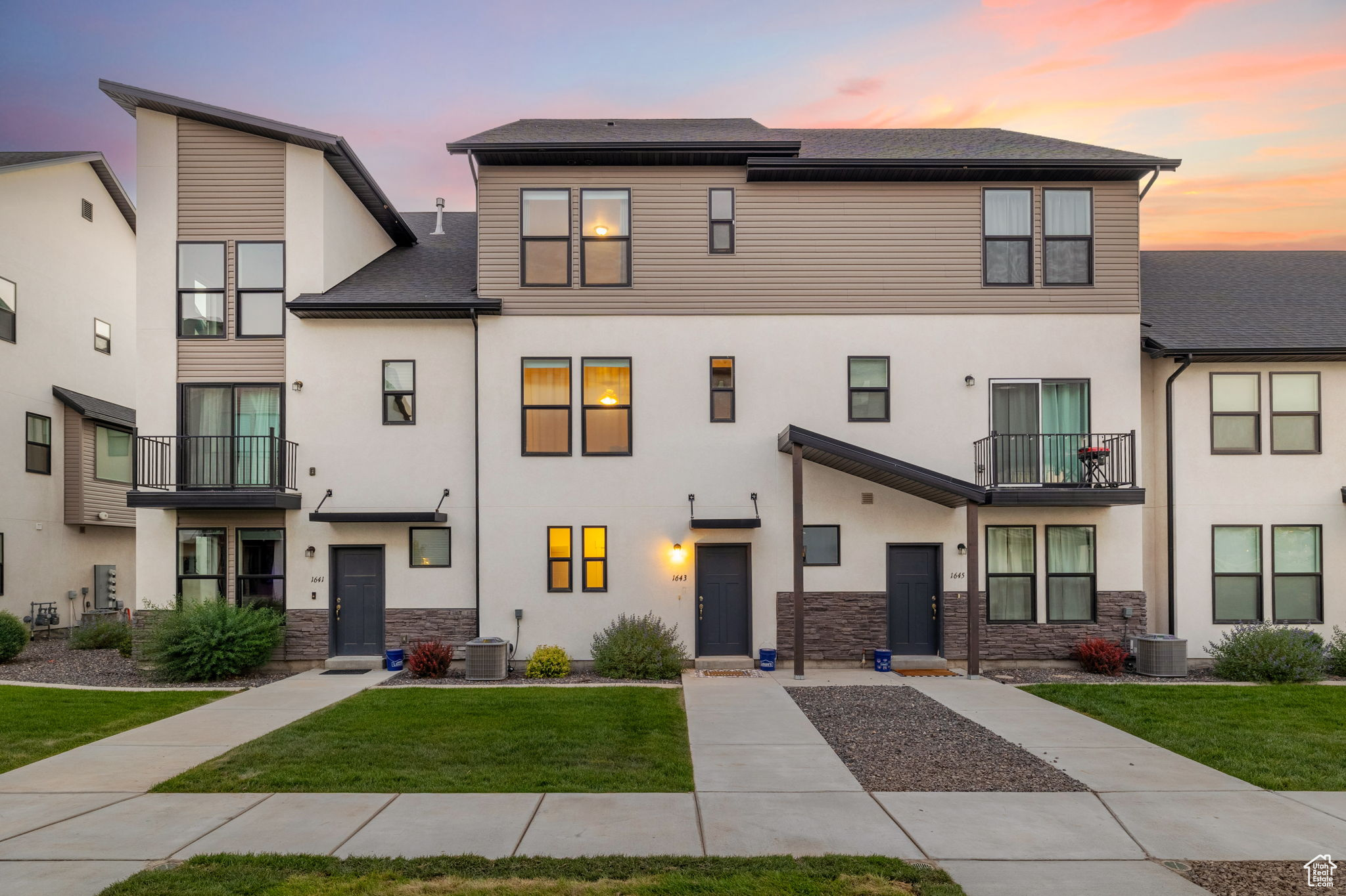 View of front of house featuring a balcony, a yard, and central AC