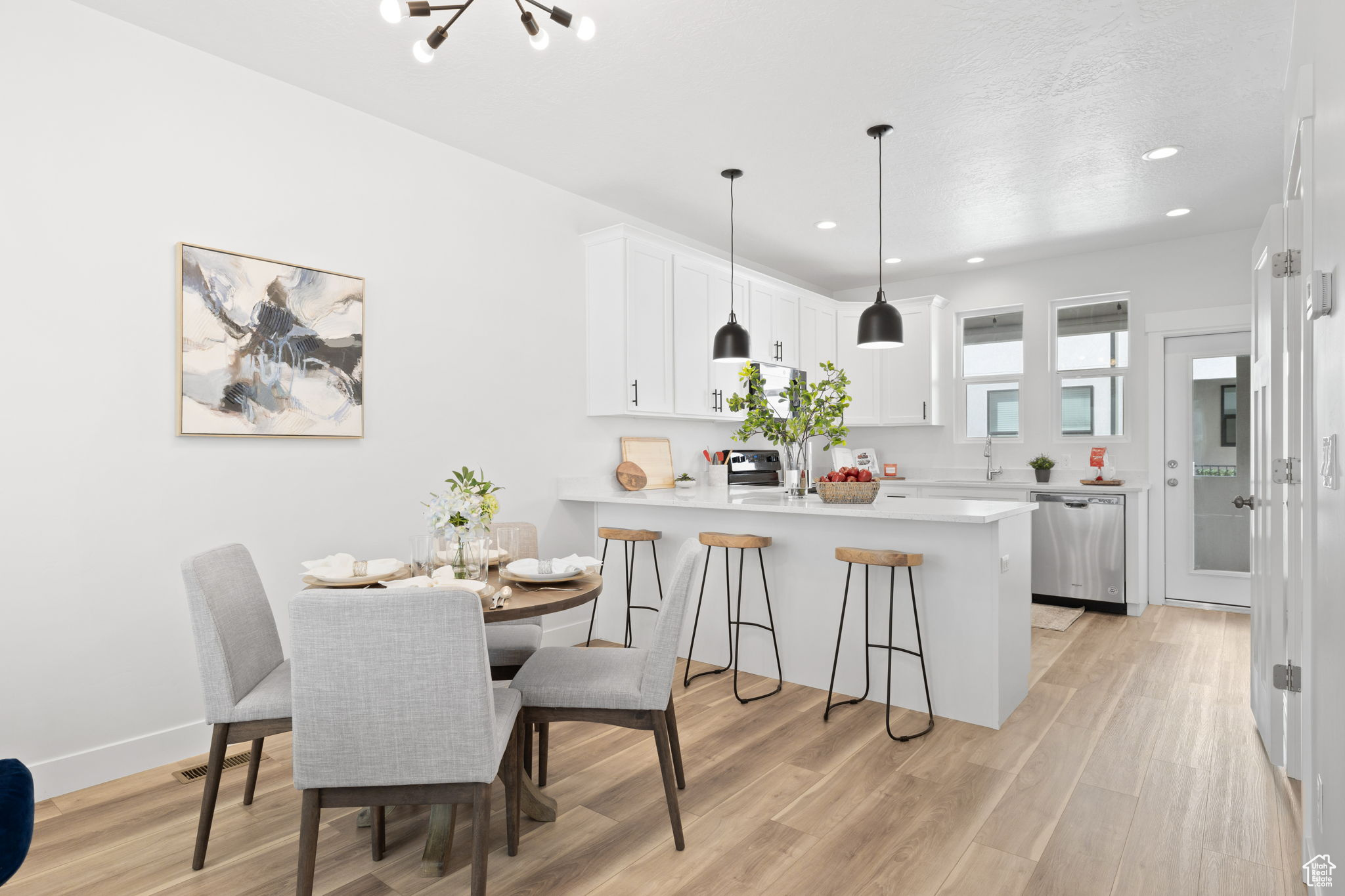 Dining space with a textured ceiling, sink, light wood-type flooring, and an inviting chandelier