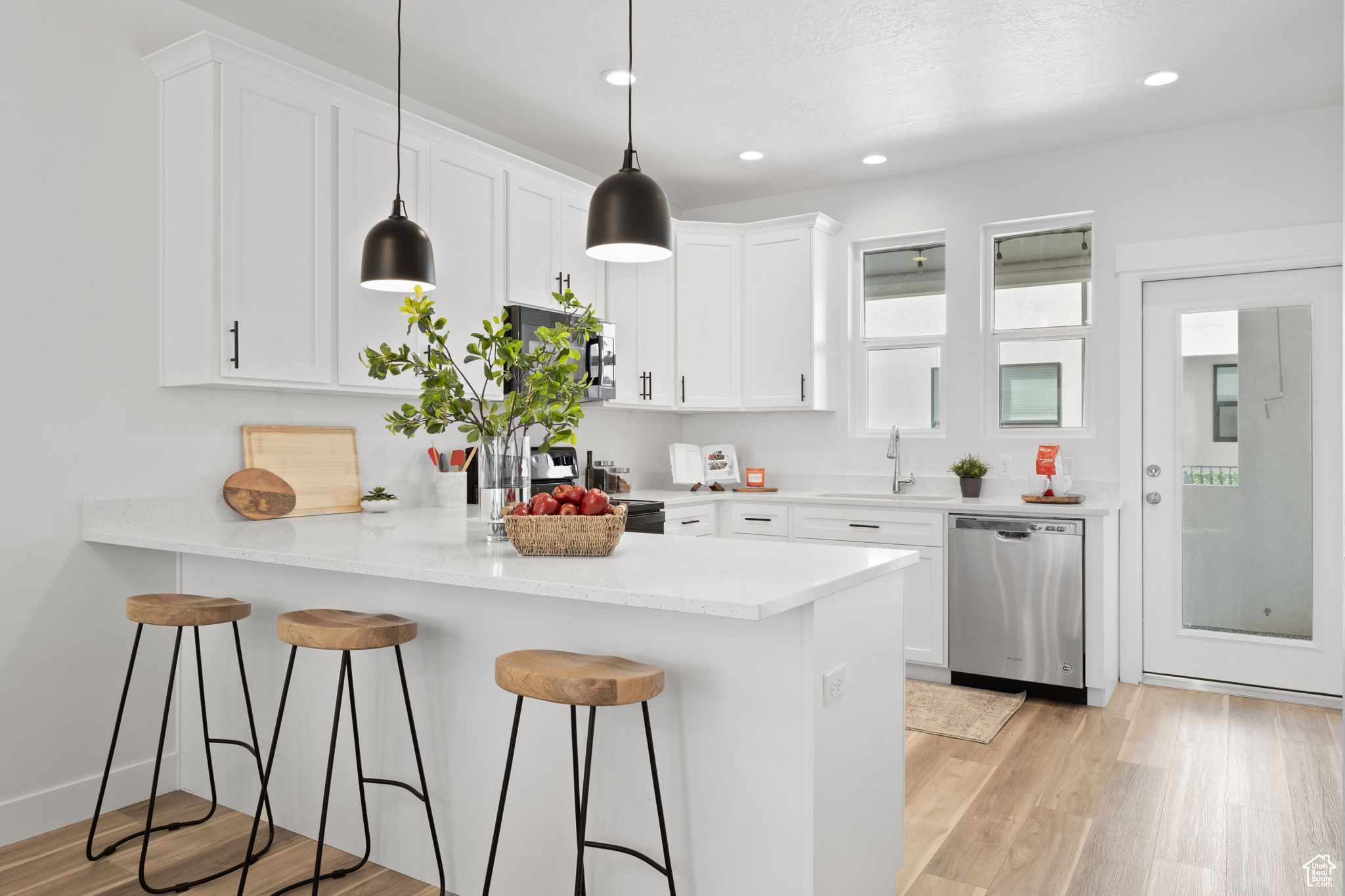 Kitchen featuring appliances with stainless steel finishes, white cabinetry, light hardwood / wood-style flooring, and kitchen peninsula