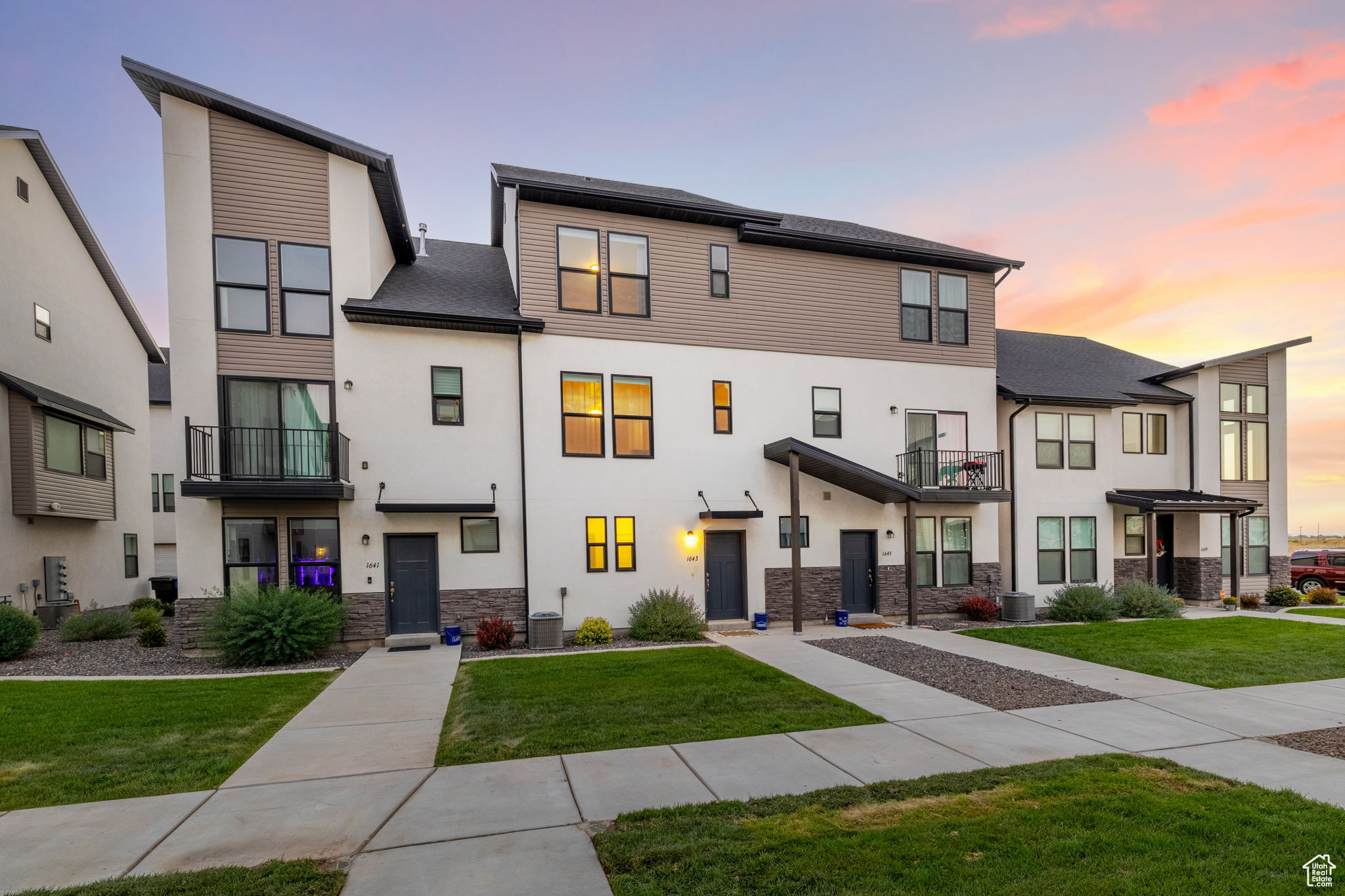 View of front of property featuring a lawn, a balcony, and central air condition unit