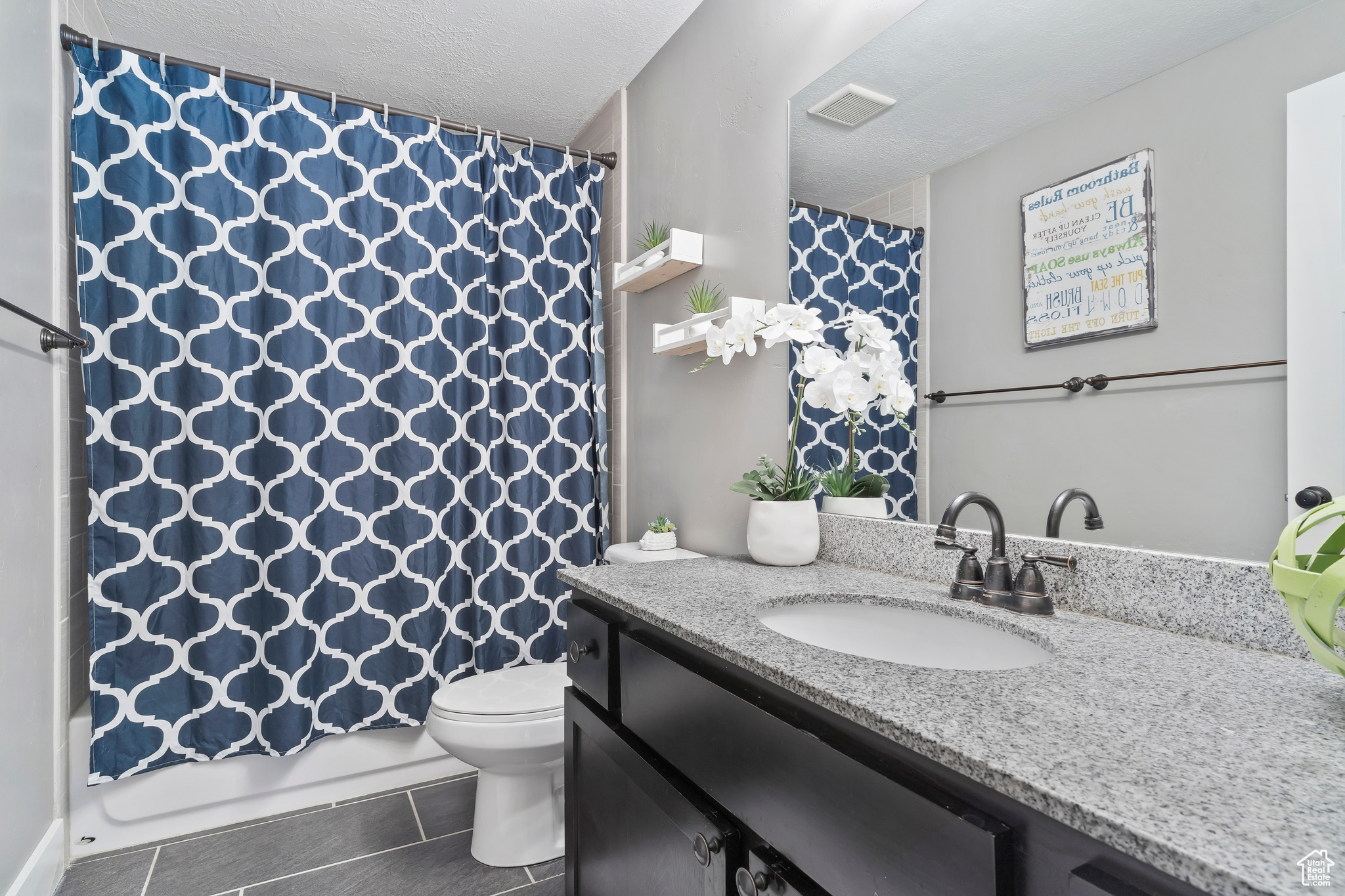 Full bathroom with shower / bath combination with curtain, vanity, a textured ceiling, tile patterned floors, and toilet