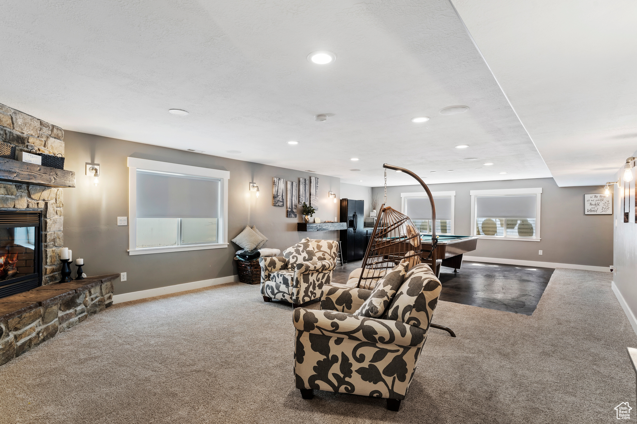 Living room featuring pool table, light colored carpet, and a stone fireplace