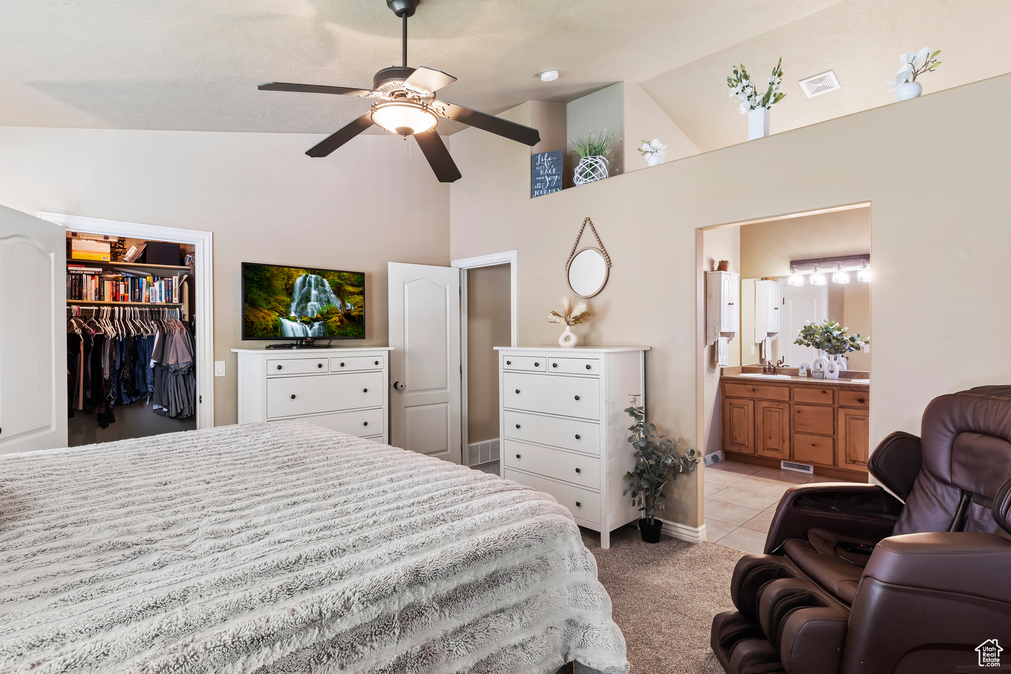 Bedroom featuring a closet, ceiling fan, a walk in closet, ensuite bath, and light carpet