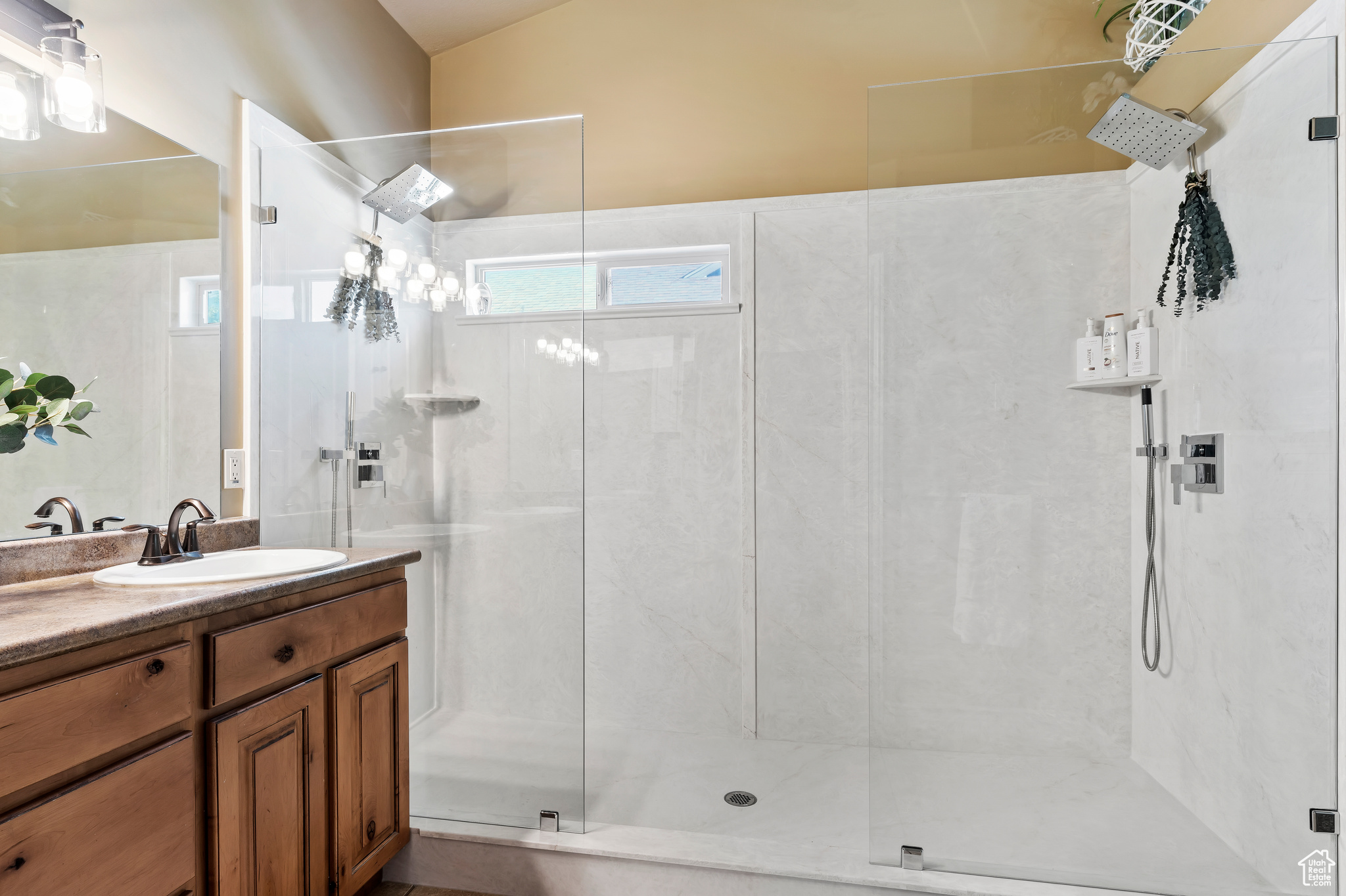 Bathroom featuring walk in shower, vanity, and vaulted ceiling