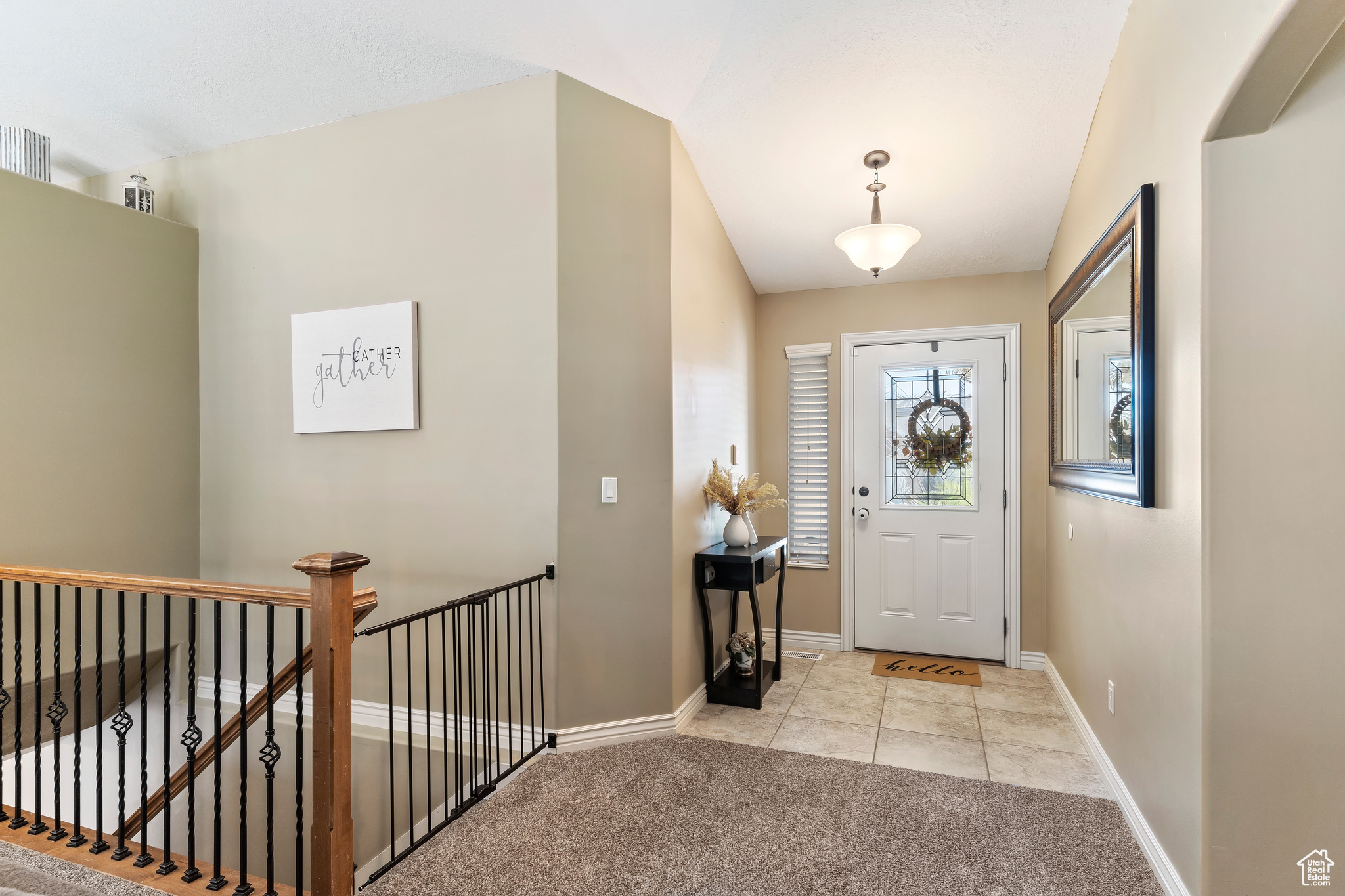 Carpeted foyer entrance featuring vaulted ceiling