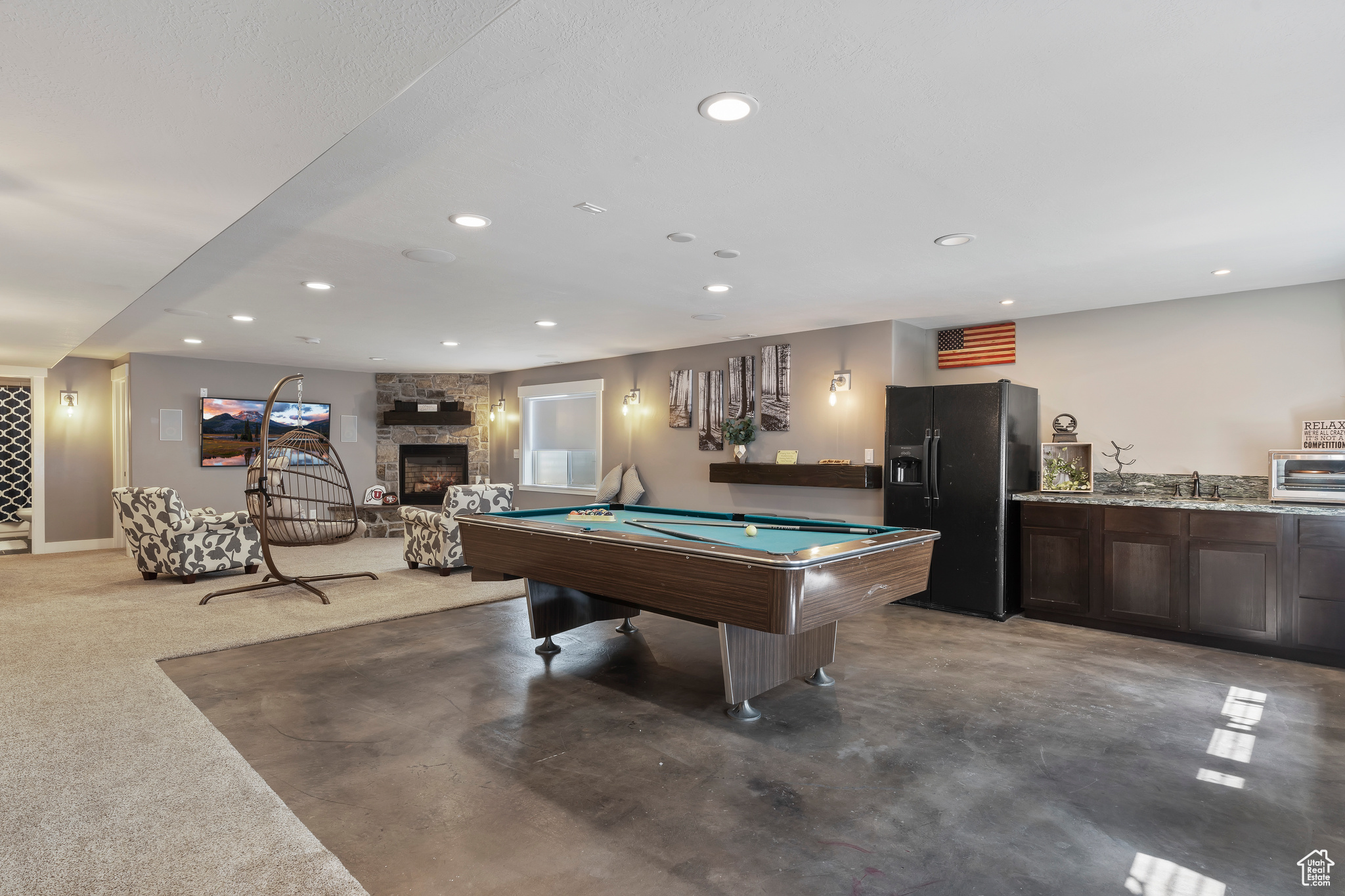 Playroom with pool table, a stone fireplace, sink, and concrete flooring