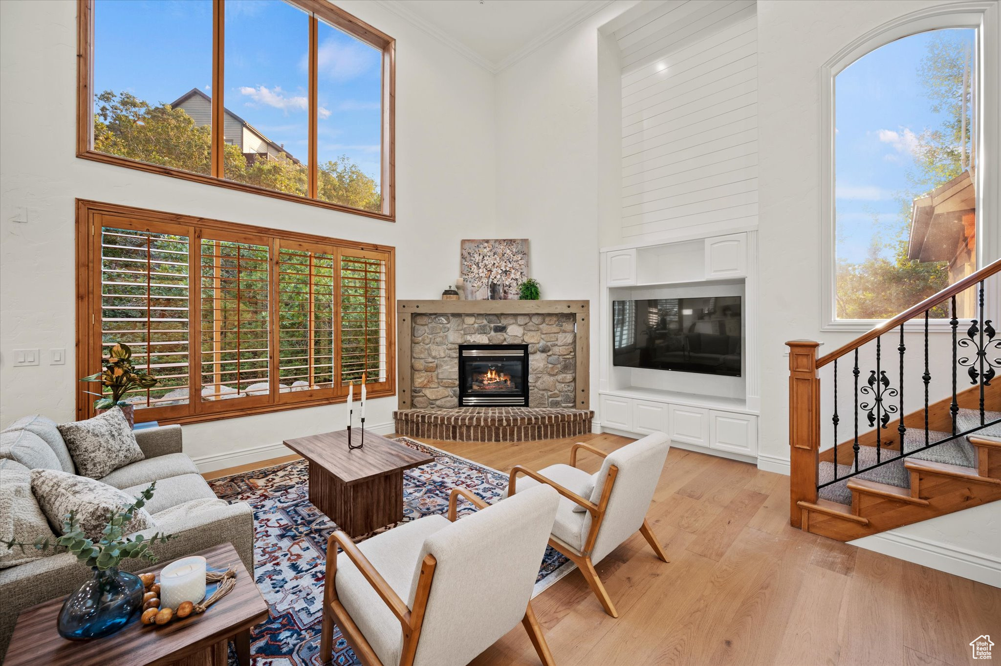 Living room featuring a fireplace, crown molding, a healthy amount of sunlight, and light hardwood / wood-style flooring