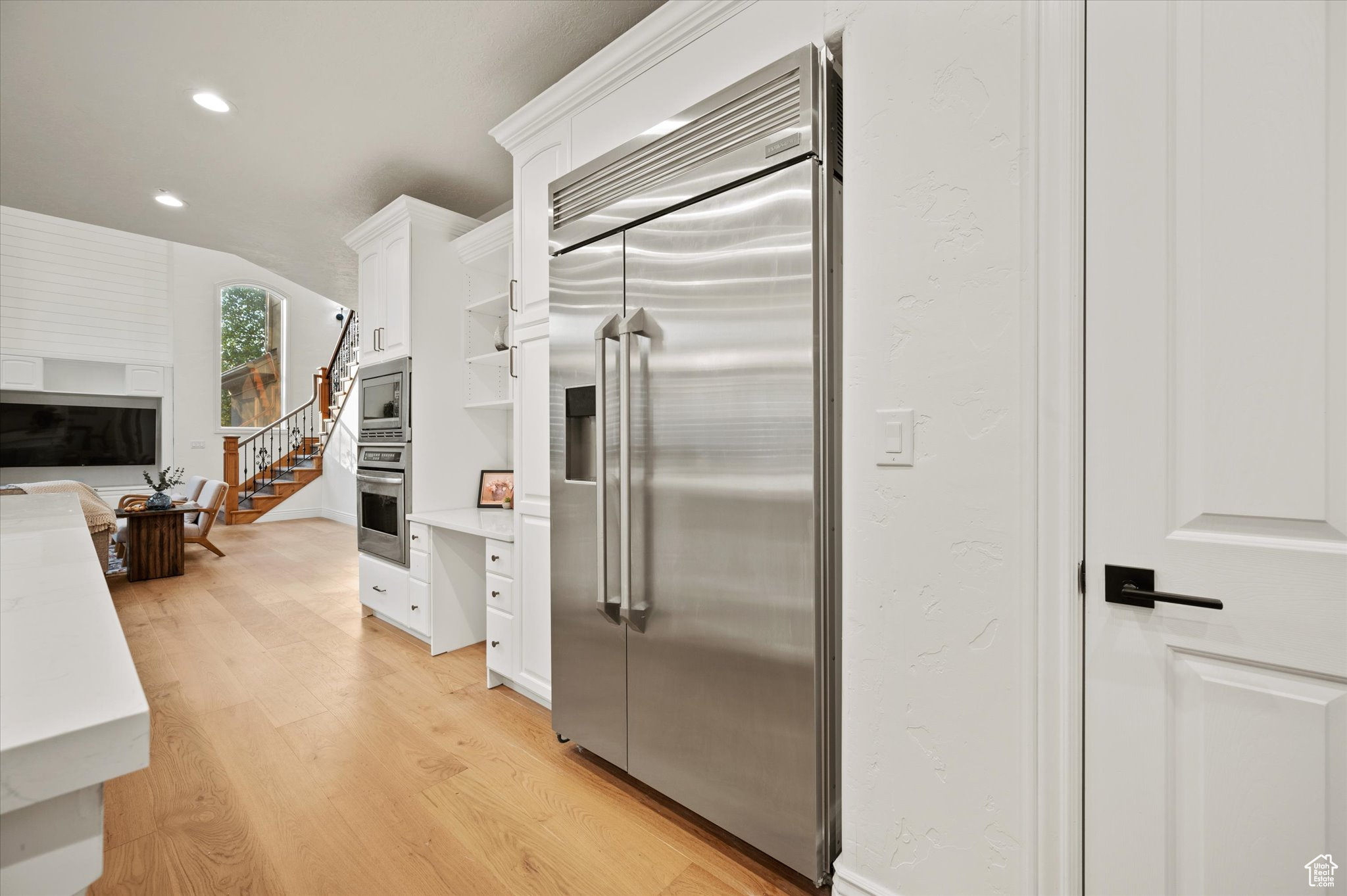 Kitchen with built in appliances, light wood-type flooring, and white cabinetry