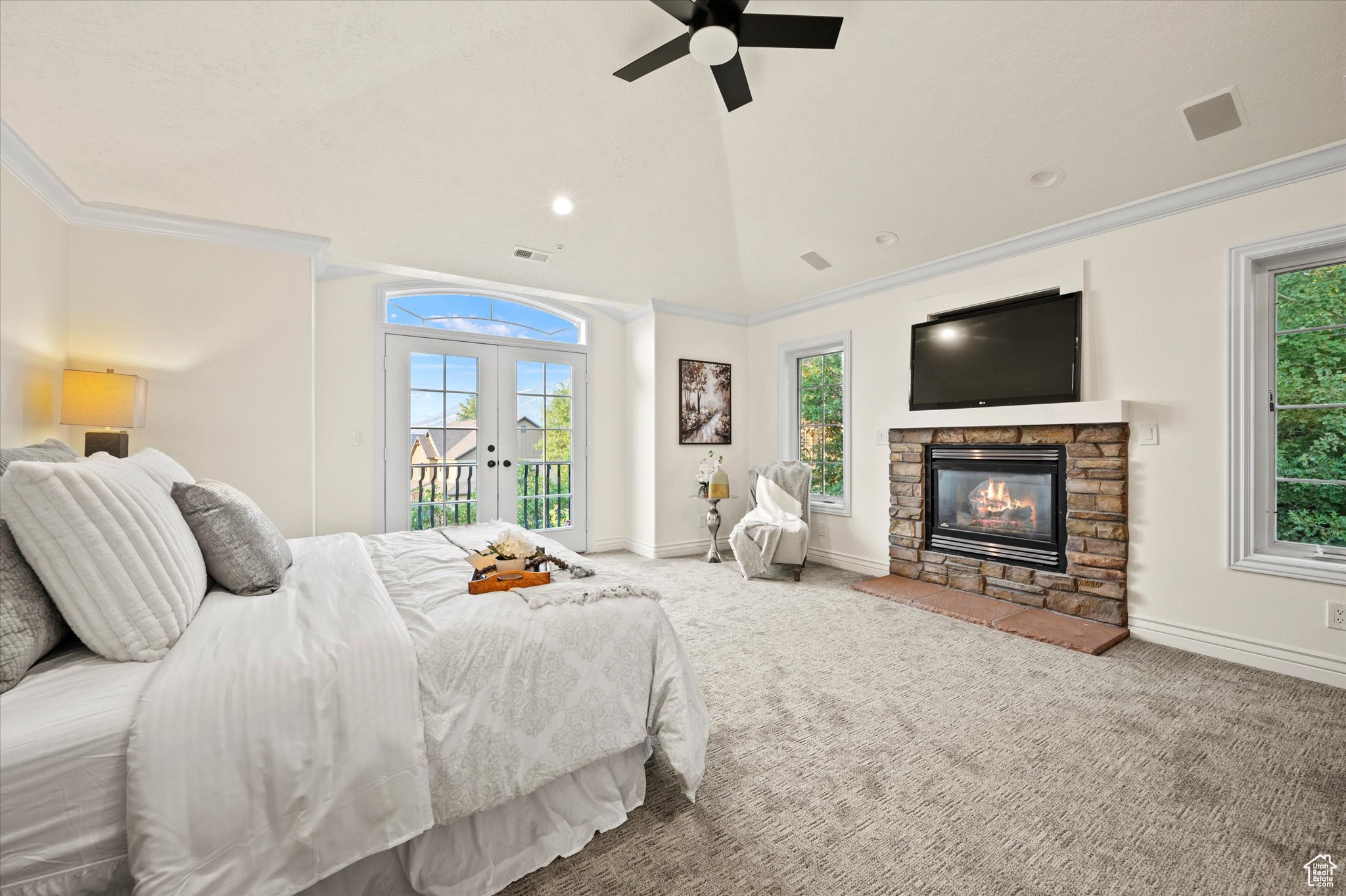 Carpeted bedroom featuring access to exterior, ceiling fan, a stone fireplace, french doors, and lofted ceiling