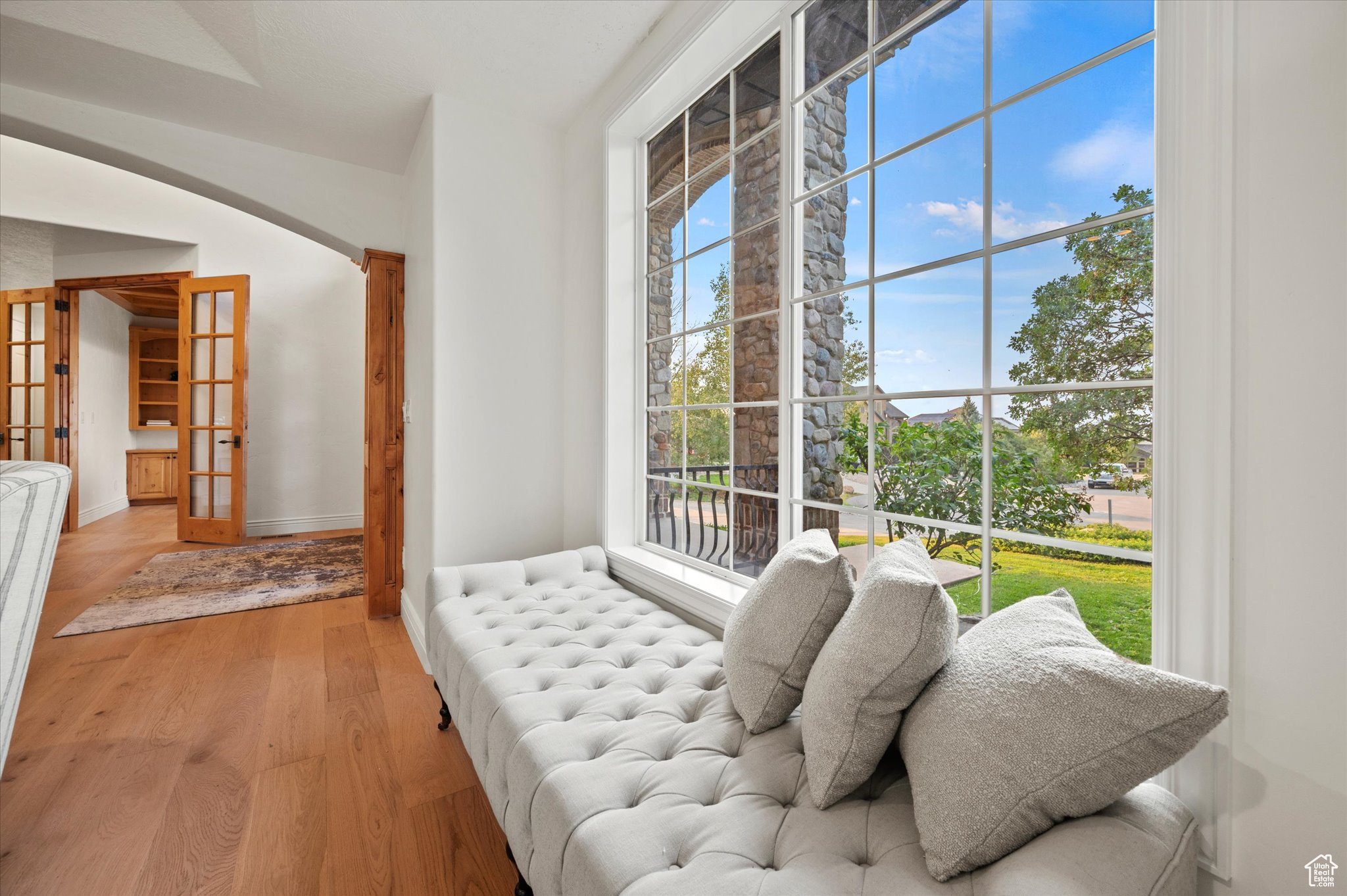 Sitting room with a wealth of natural light, light wood-type flooring, and french doors