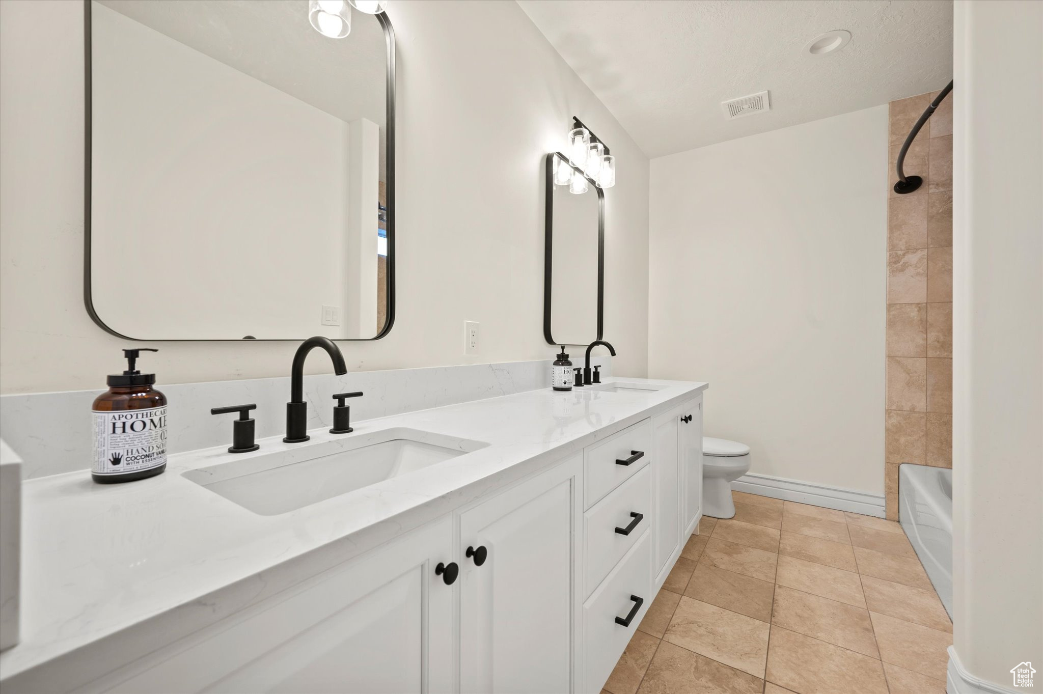 Full bathroom with tiled shower / bath combo, vanity, toilet, and tile patterned floors