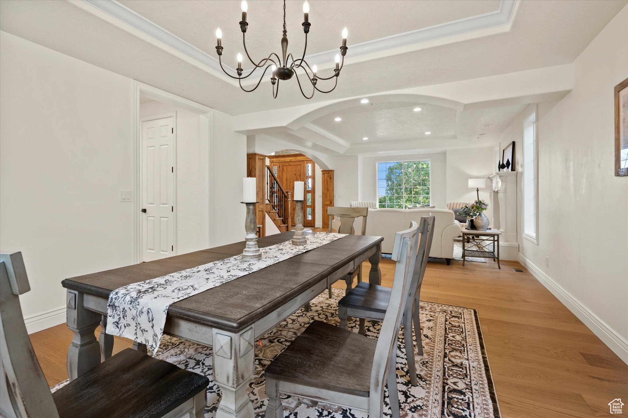 Dining room with ornamental molding, a raised ceiling, light hardwood / wood-style flooring, and an inviting chandelier