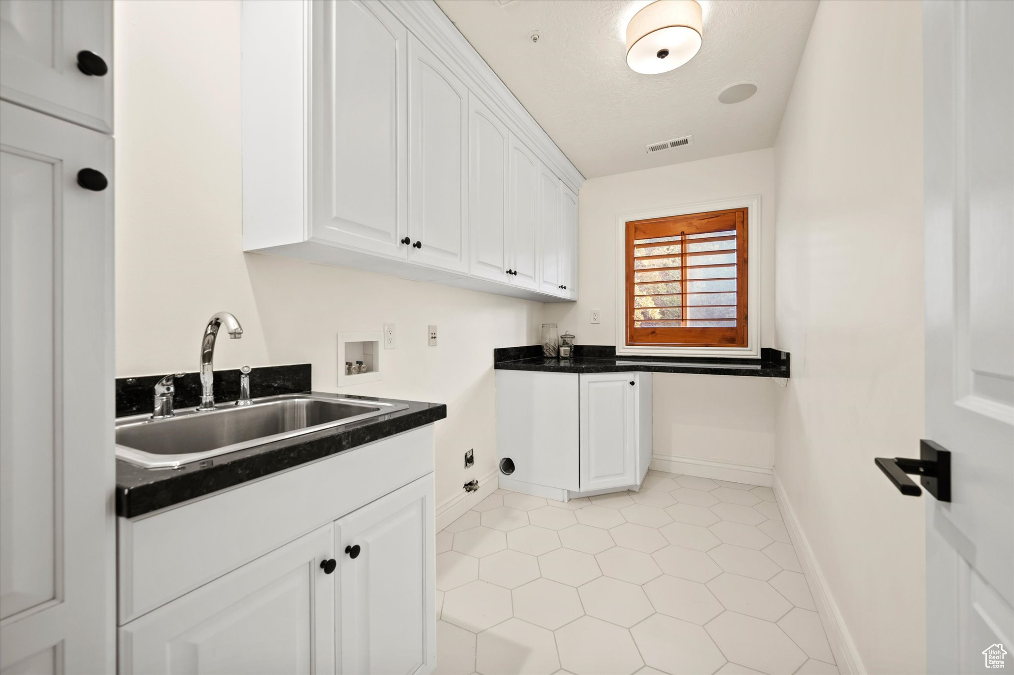 Interior space featuring hookup for a washing machine, cabinets, light tile patterned floors, sink, and hookup for a gas dryer