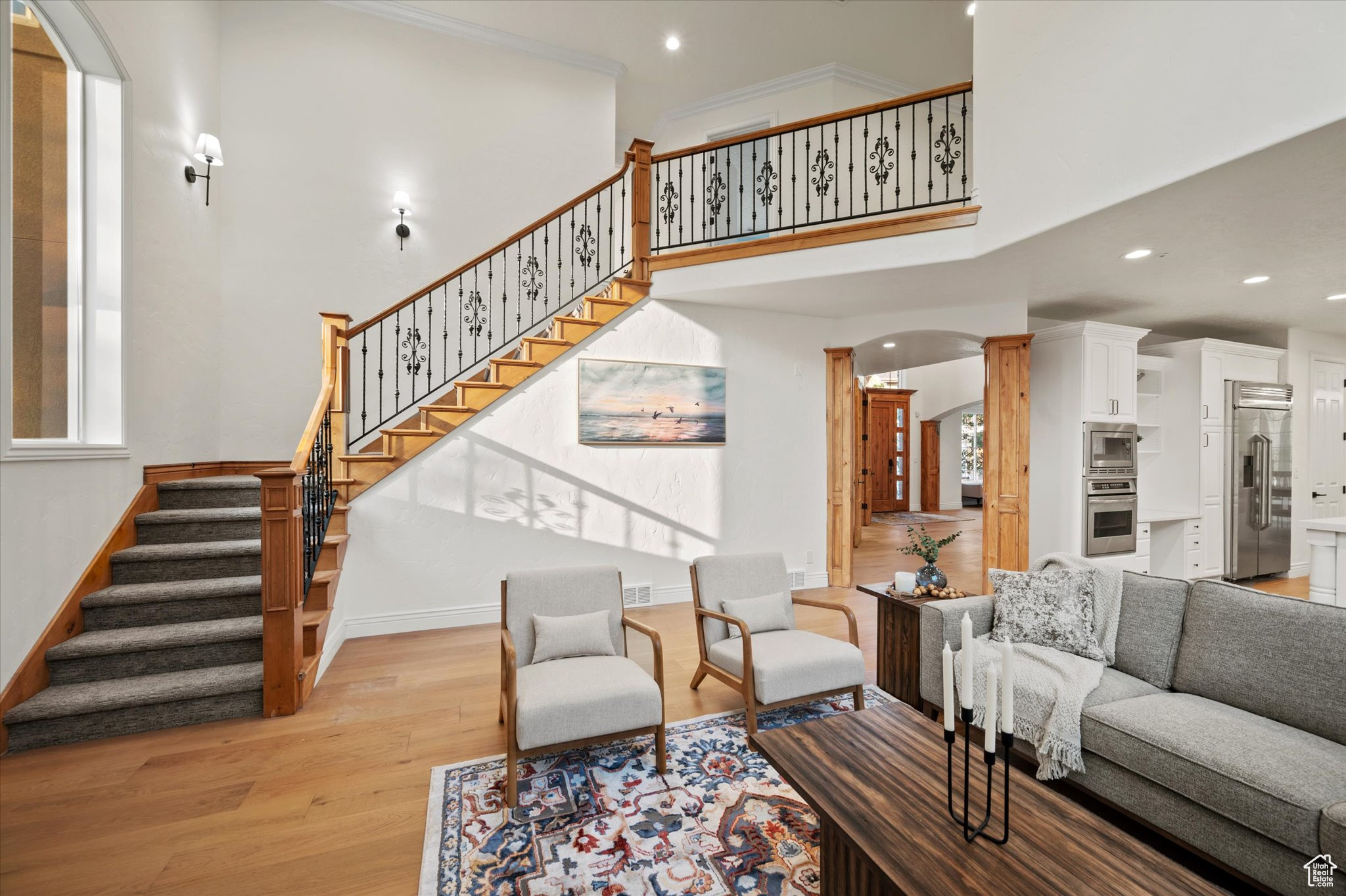 Living room with a wealth of natural light, crown molding, a high ceiling, and light hardwood / wood-style floors