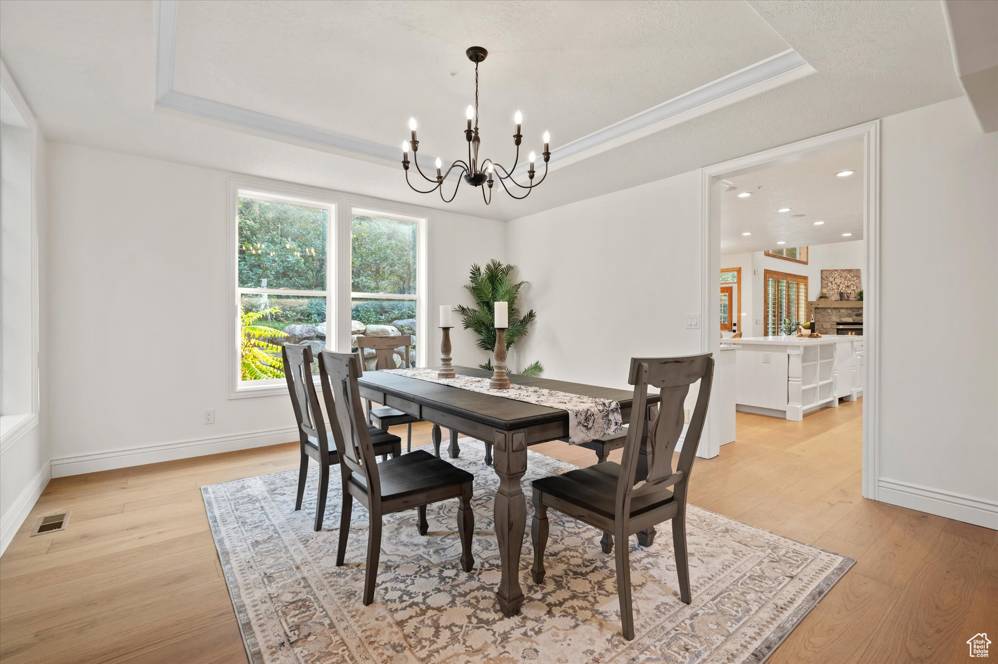 Dining space featuring light wood-type flooring, a raised ceiling